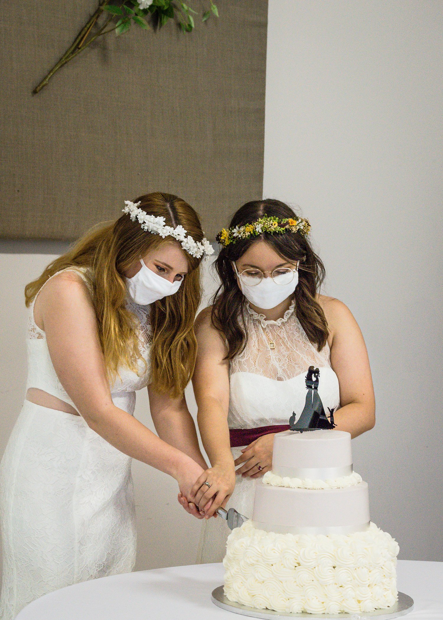 A newlywed LGBTQ+ couple cuts into their wedding cake.