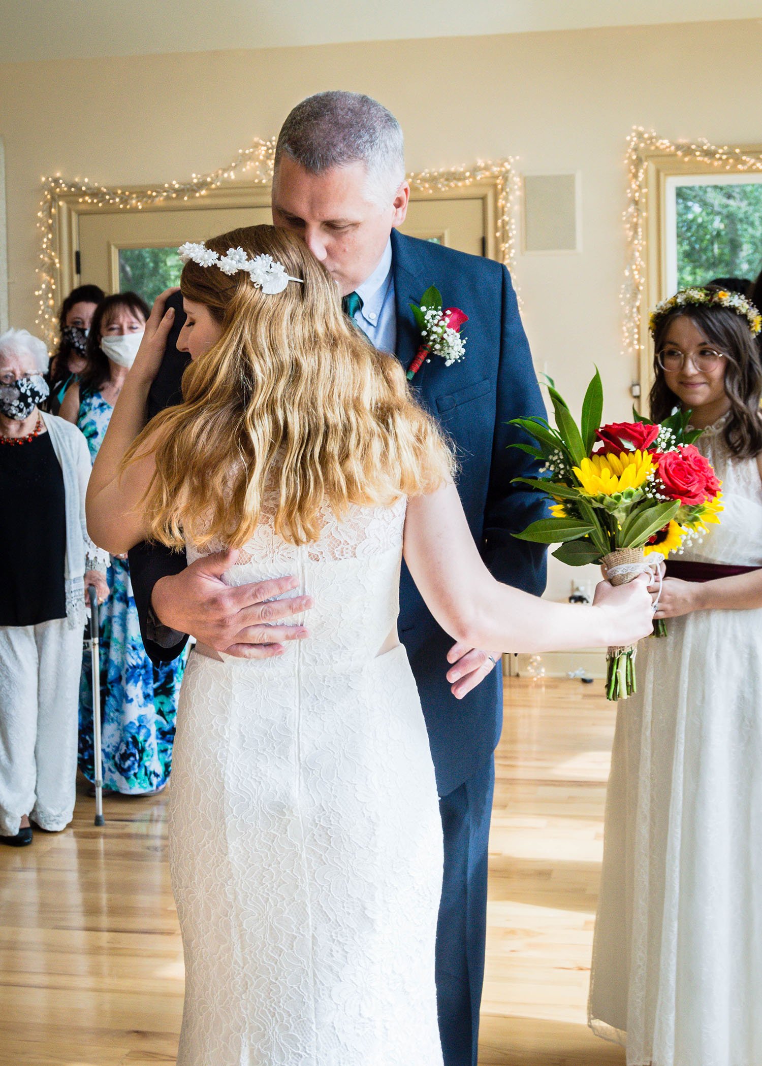 The father of the marrier kisses their child's head as the marrier goes in for a hug.