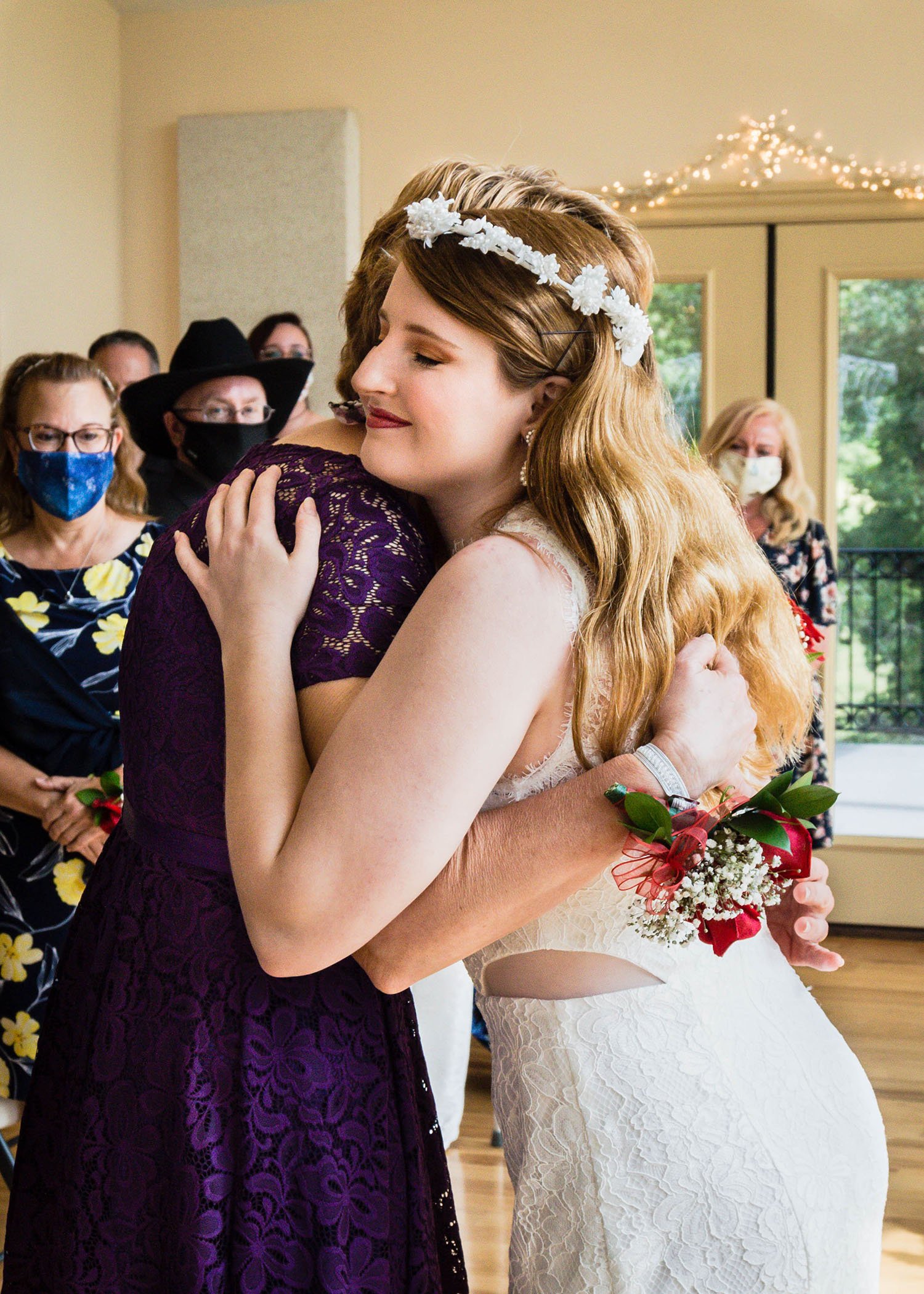 The mother of the marrier and the marrier embrace at the front of the room during the ceremony.