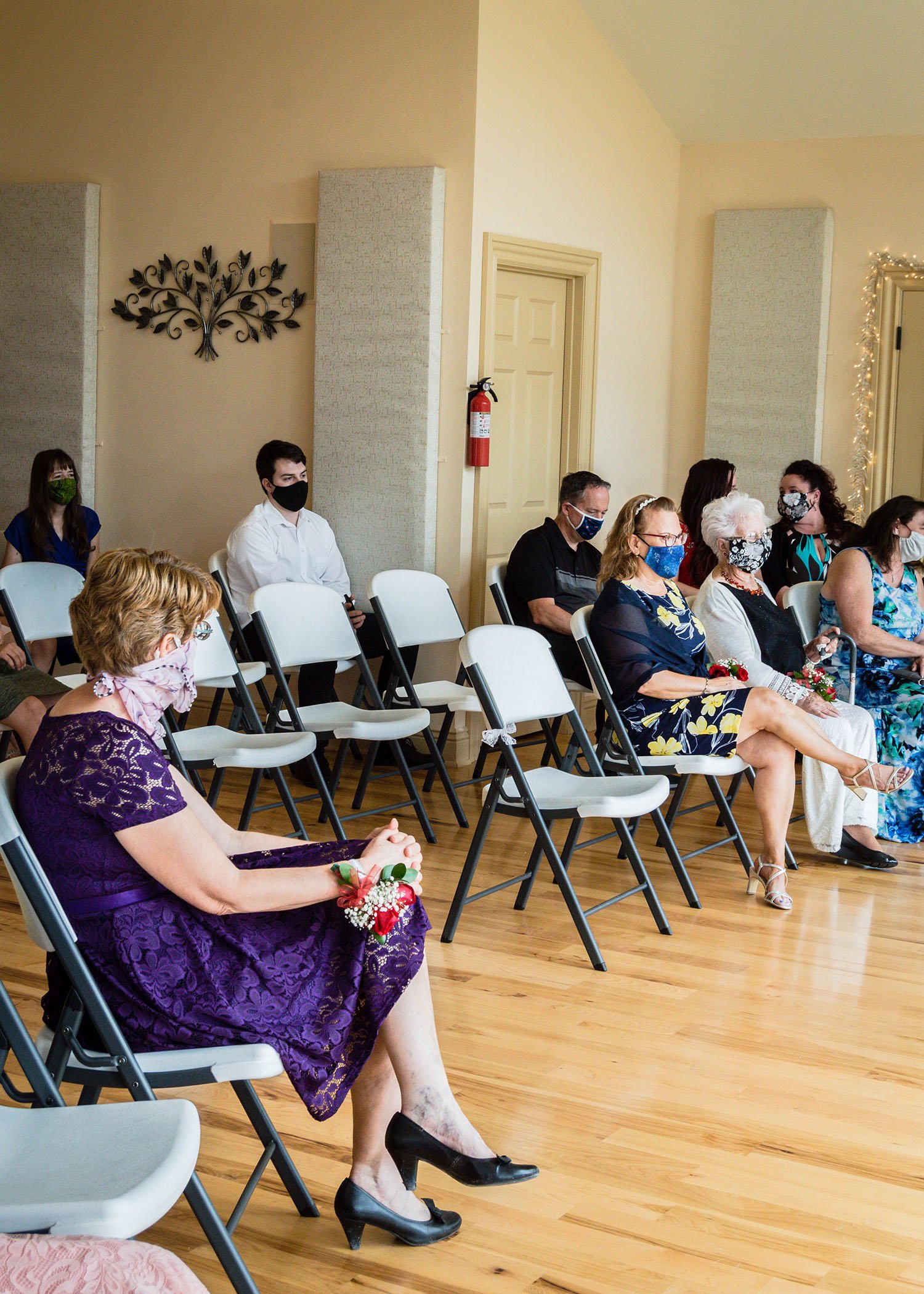 The mother of the brides, grandmother of one of the brides, and a few guests sit in their seats ahead of the wedding ceremony.