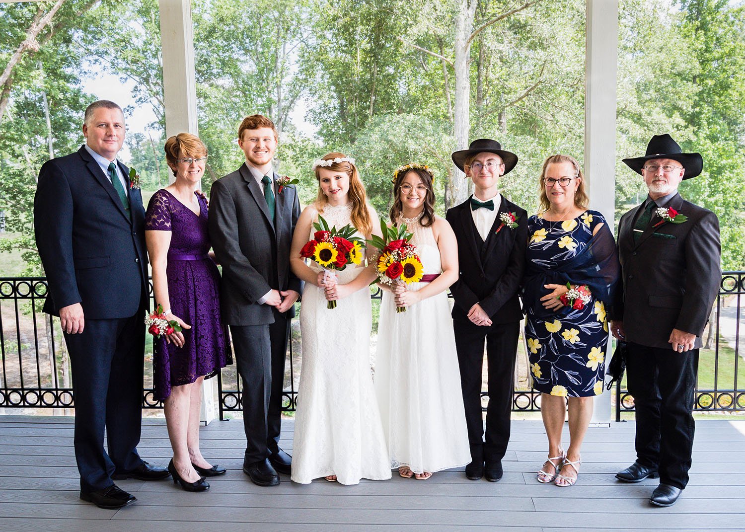 Two newlywed LGBTQ+ marriers stand between their two families for a combined family group shot following the ceremony.