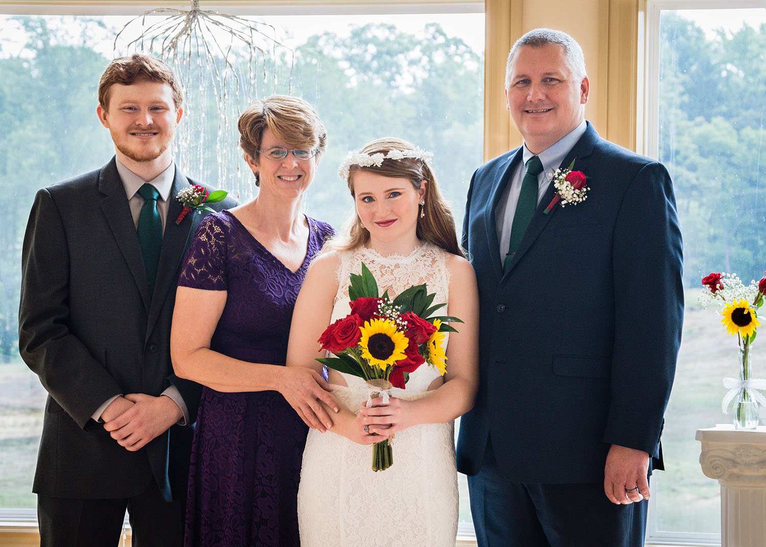 An LGBTQ marrier stands inside the wedding venue at Davidson Farm for a photo with their father, mother, and brother.