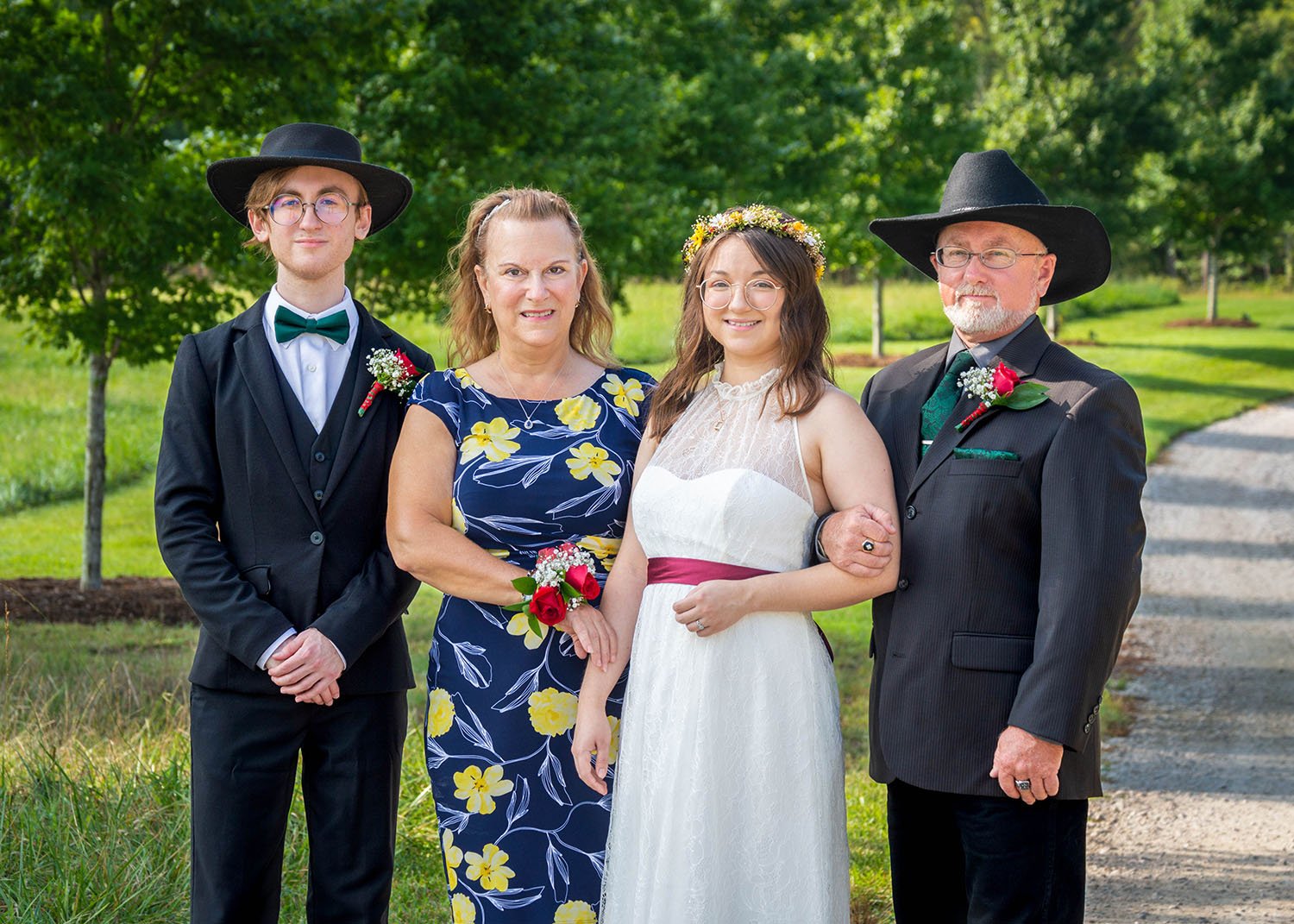 An LGBTQ bride stands next to her father, mother, and sibling for a photo on the property of Davidson Farm, a wedding venue in South Carolina.