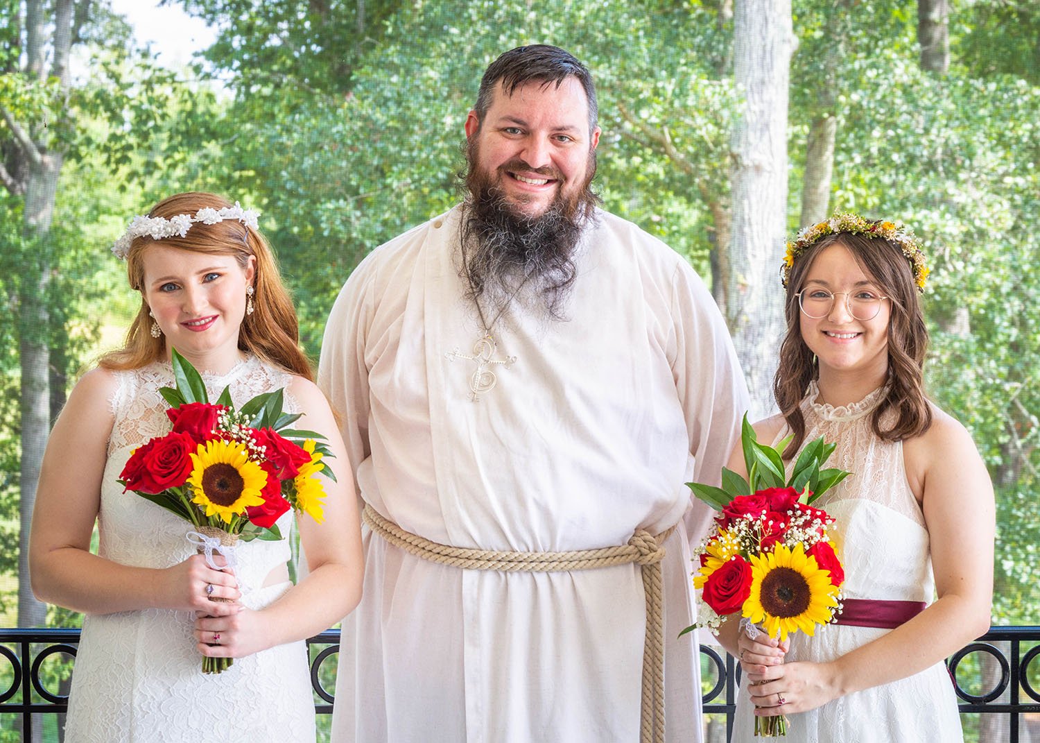 Two LGBTQ+ marriers stand next to their officiant after their wedding ceremony for a photo.