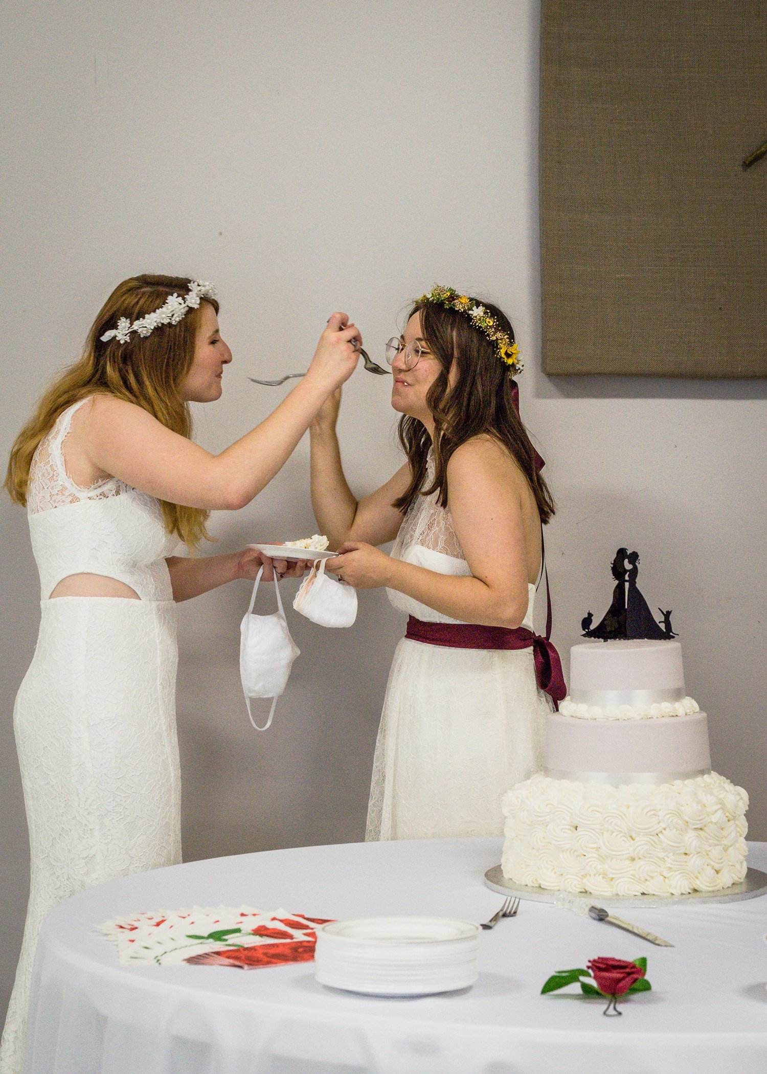 Two LGBTQ+ marriers feed a piece of freshly sliced cake to one another.