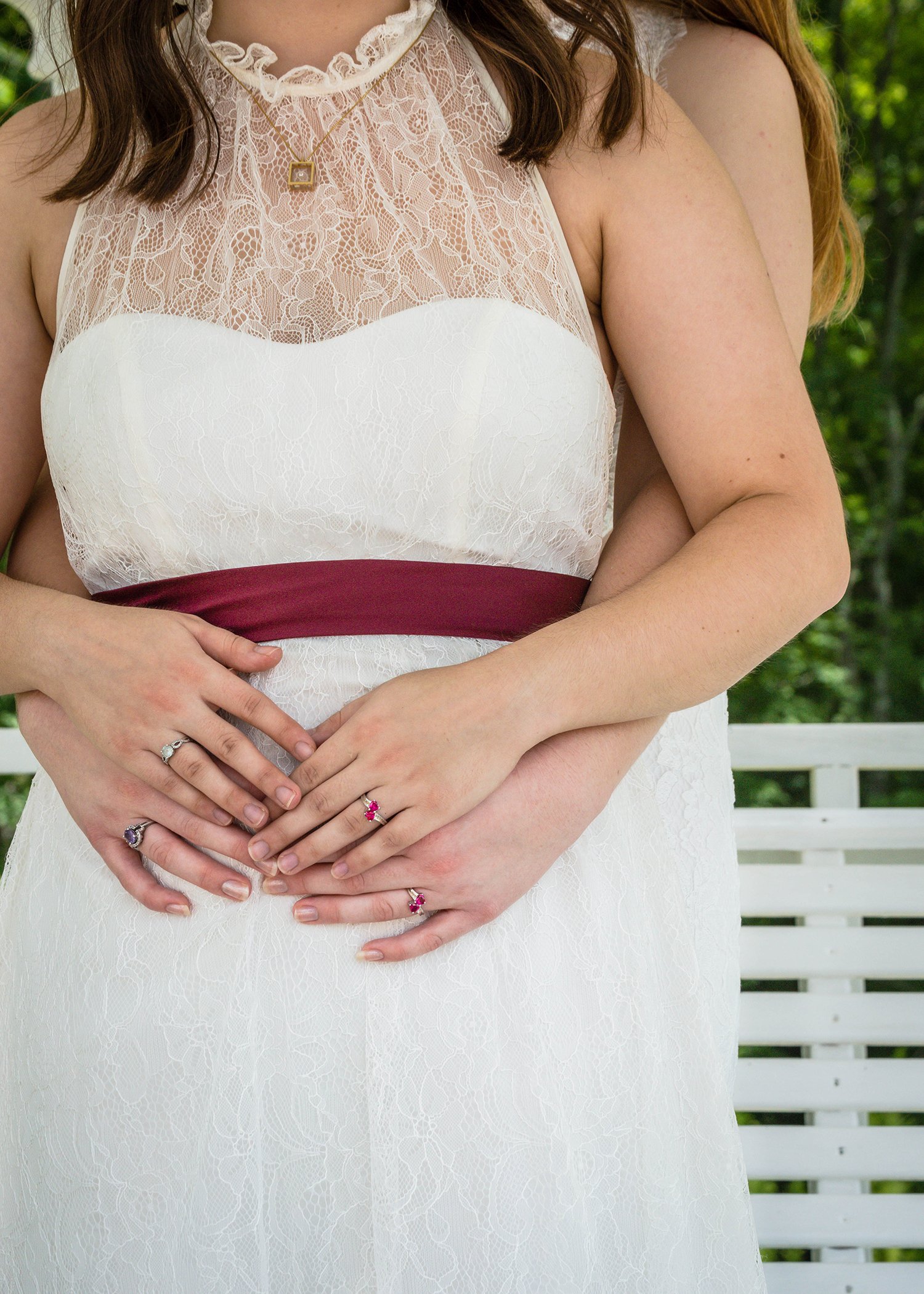 Two LGBTQ+ marriers embrace and intertwine their fingers together.