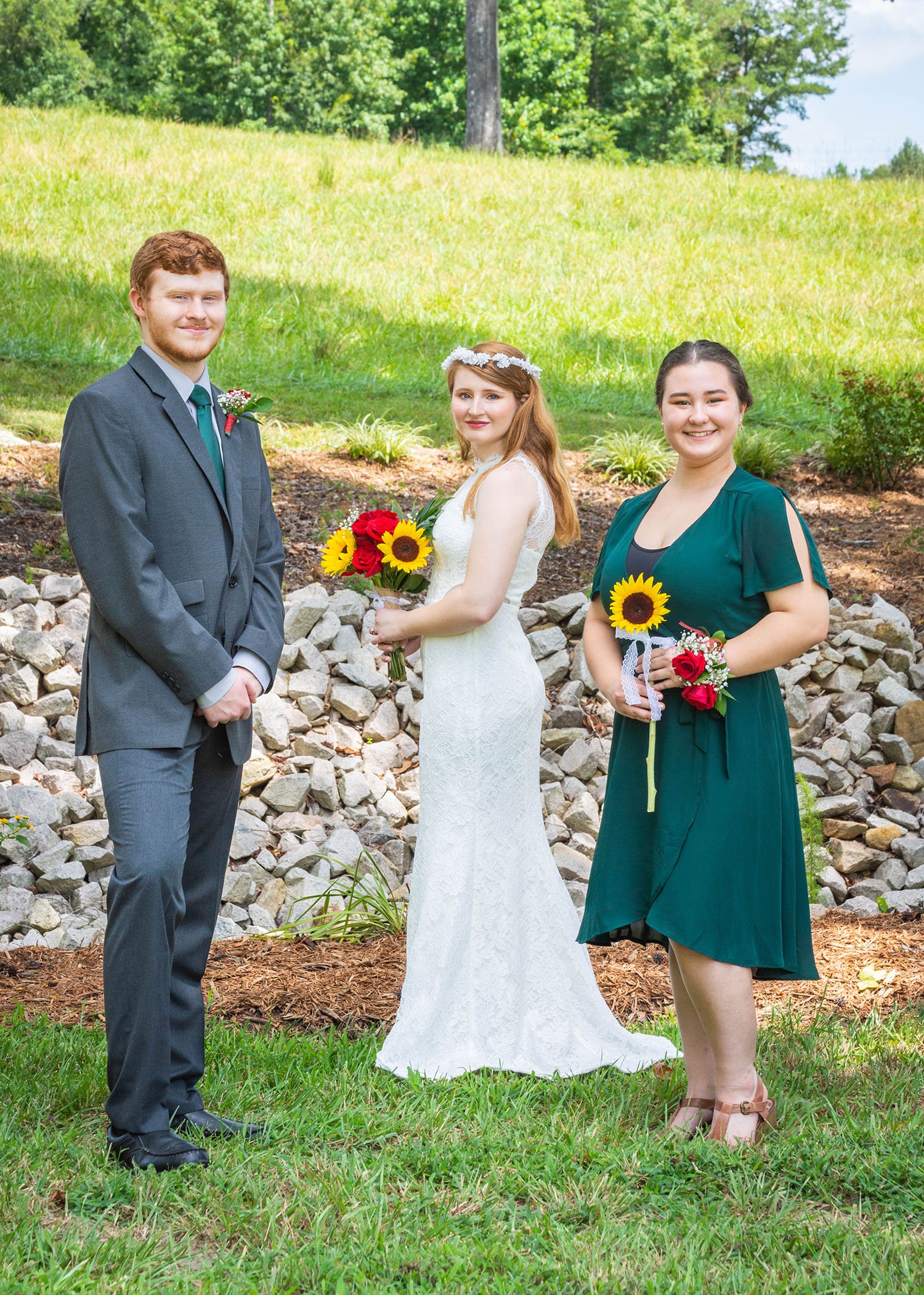 An LGBTQ+ bride stands between two members of their wedding party.