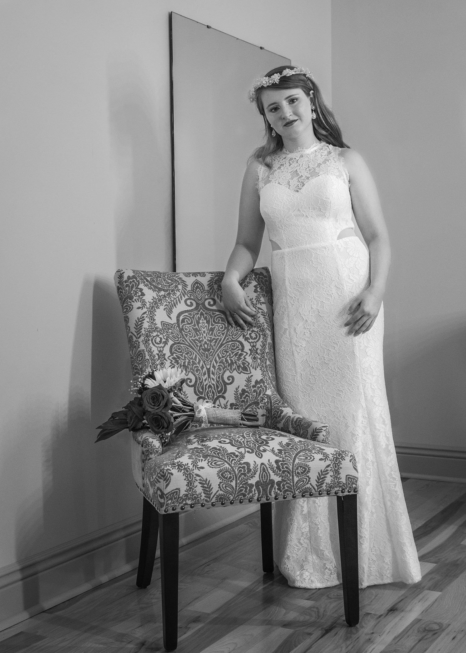 A queer marrier stands inside propped behind a chair inside the bridal suite at Davidson Farm. In the chair lies their bouquet.