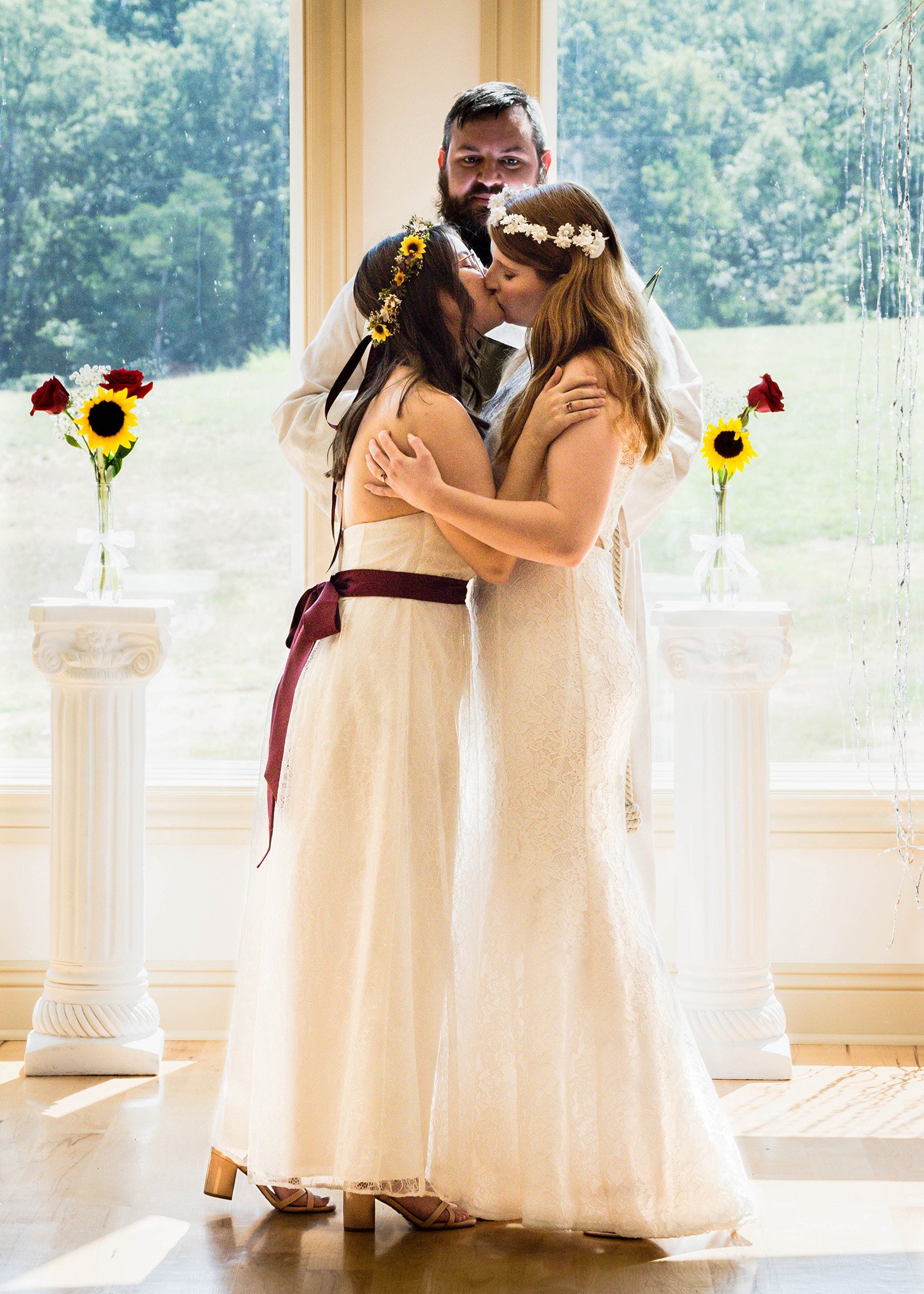 An LGBTQ+ wedding couple goes in for their first kiss as a married newlywed couple.