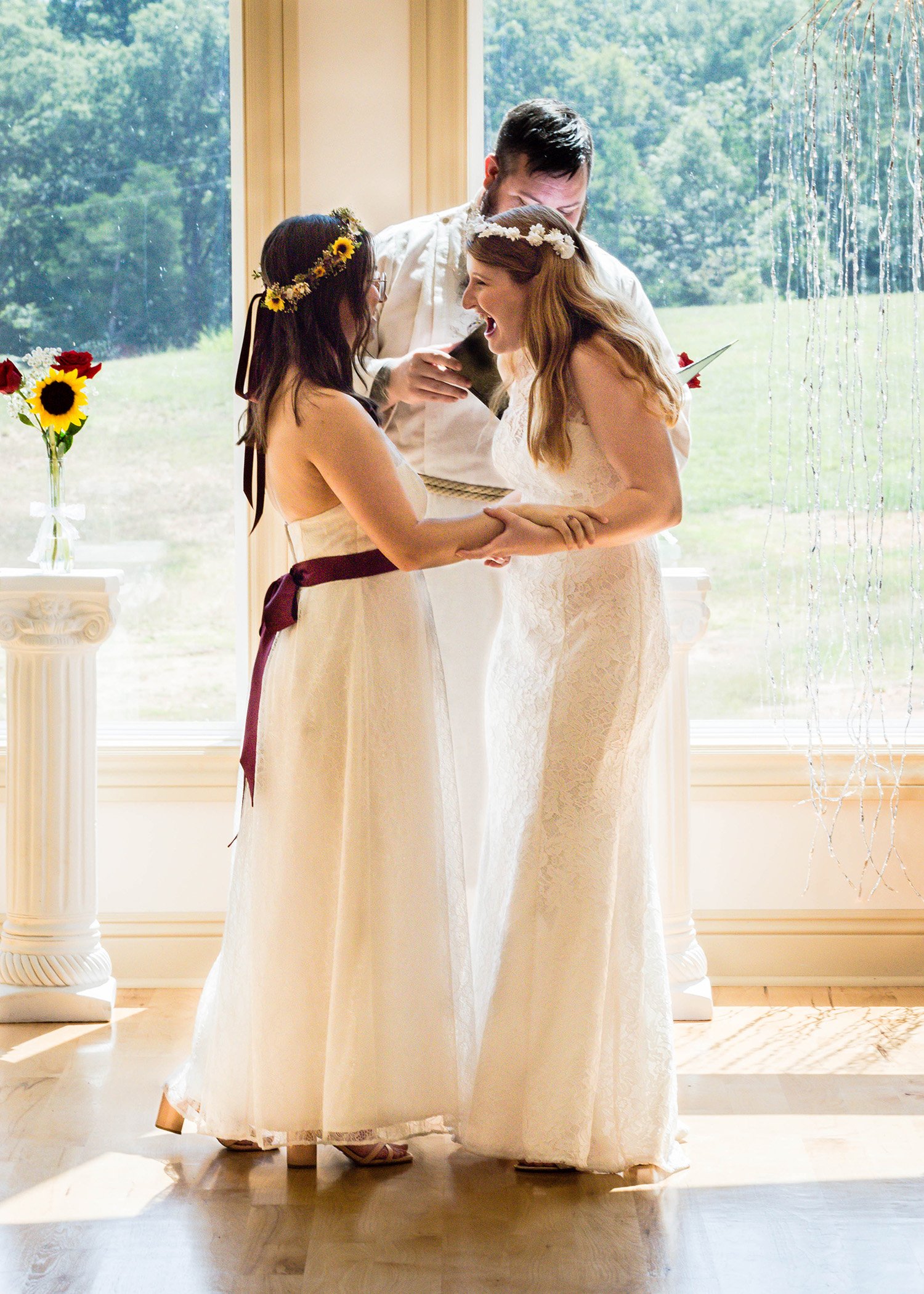 One marrier squeezes the arms of their partner and looks with them with pure joy and excitement as they finish their first kiss and wedding ceremony.