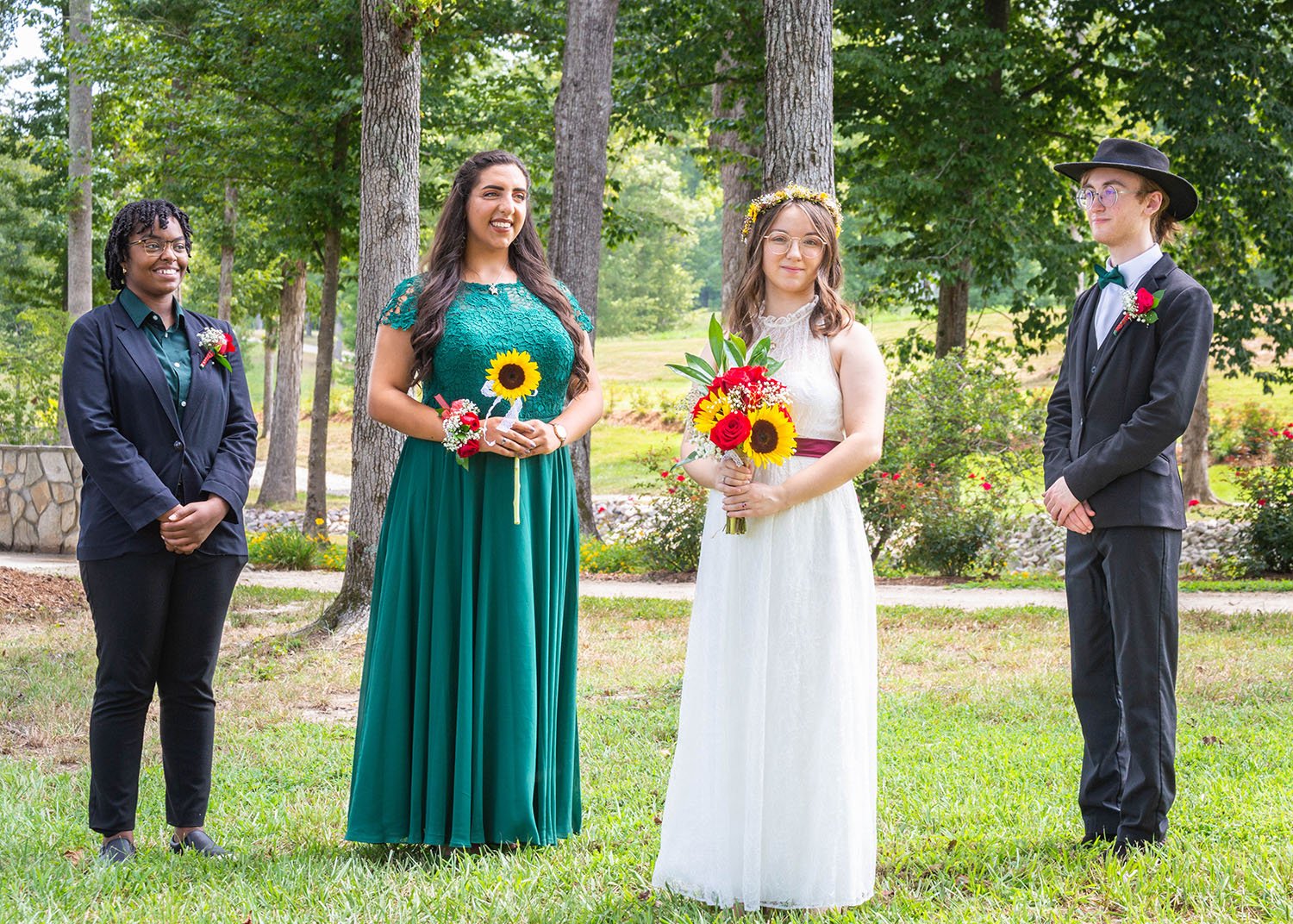 An LGBTQ+ bride stands between three of their wedding party members for a photo.