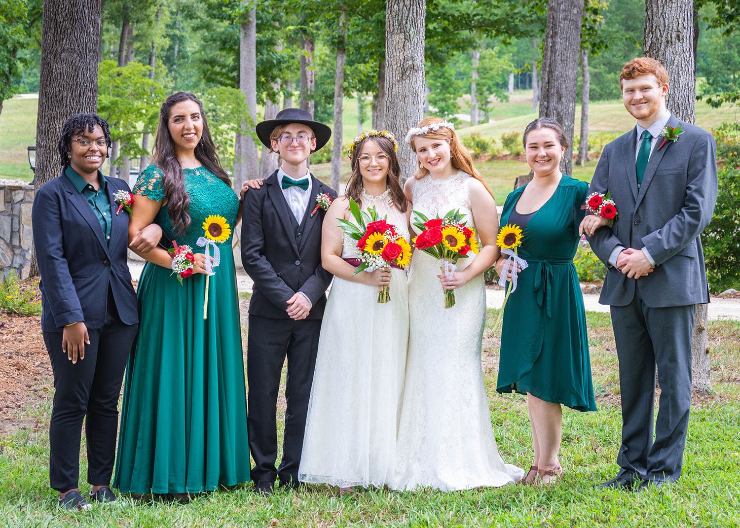 Two LGBTQ+ brides and their uneven wedding party take a photo together.