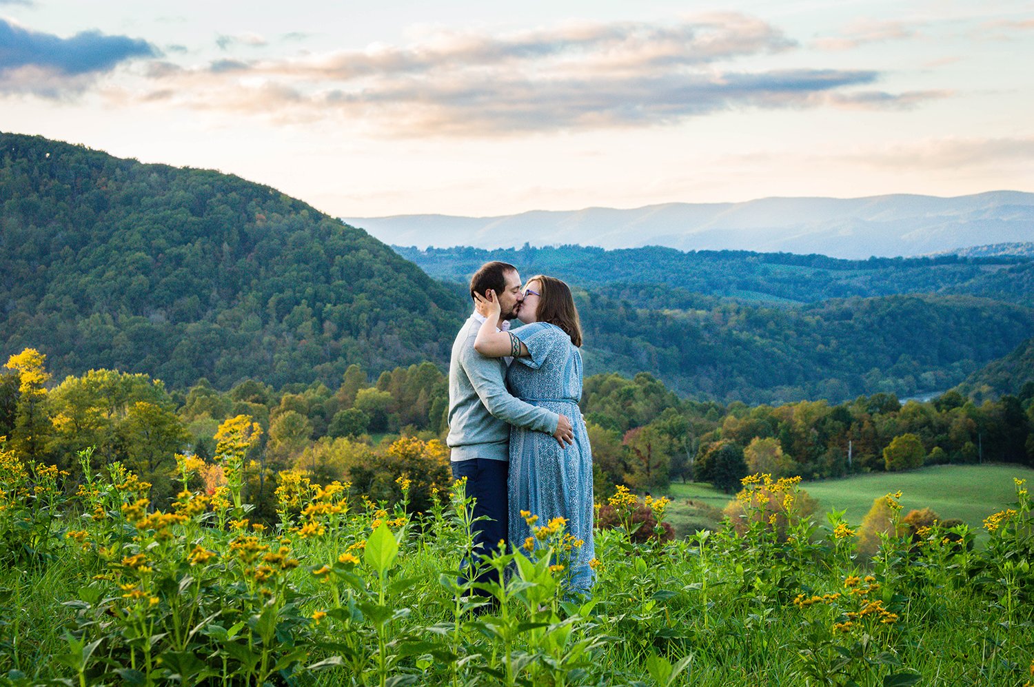  A couple kisses atop of a hill overlooking the Blue Ridge Mountains.