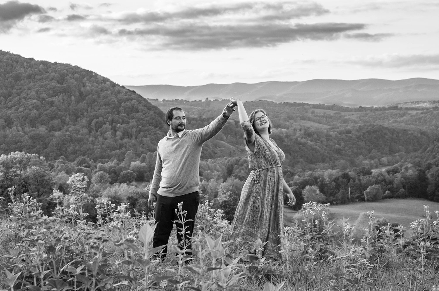 A couple dances atop of a hill overlooking the Blue Ridge Mountains.