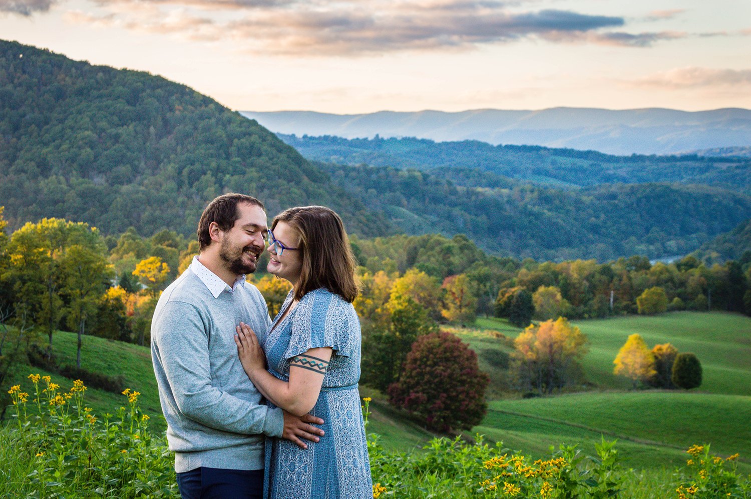 A couple embraces atop of a hill overlooking the Blue Ridge Mountains.