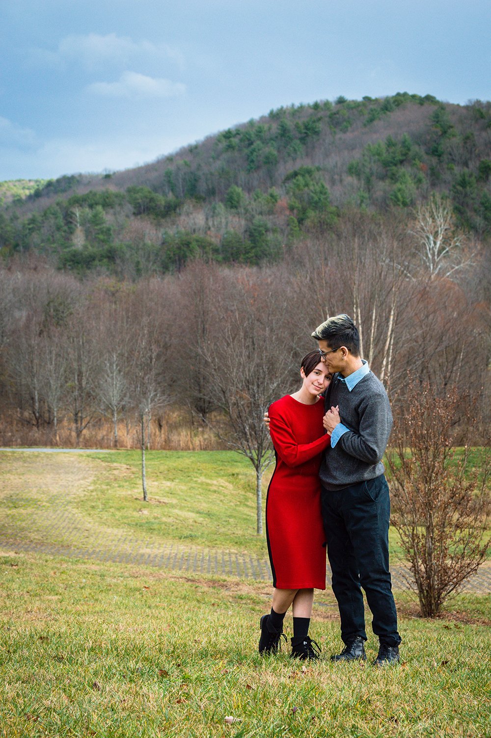 A couple embraces in front of a mountain in the background during their adventure couple’s session in Roanoke, Virginia at the South County Public Library.