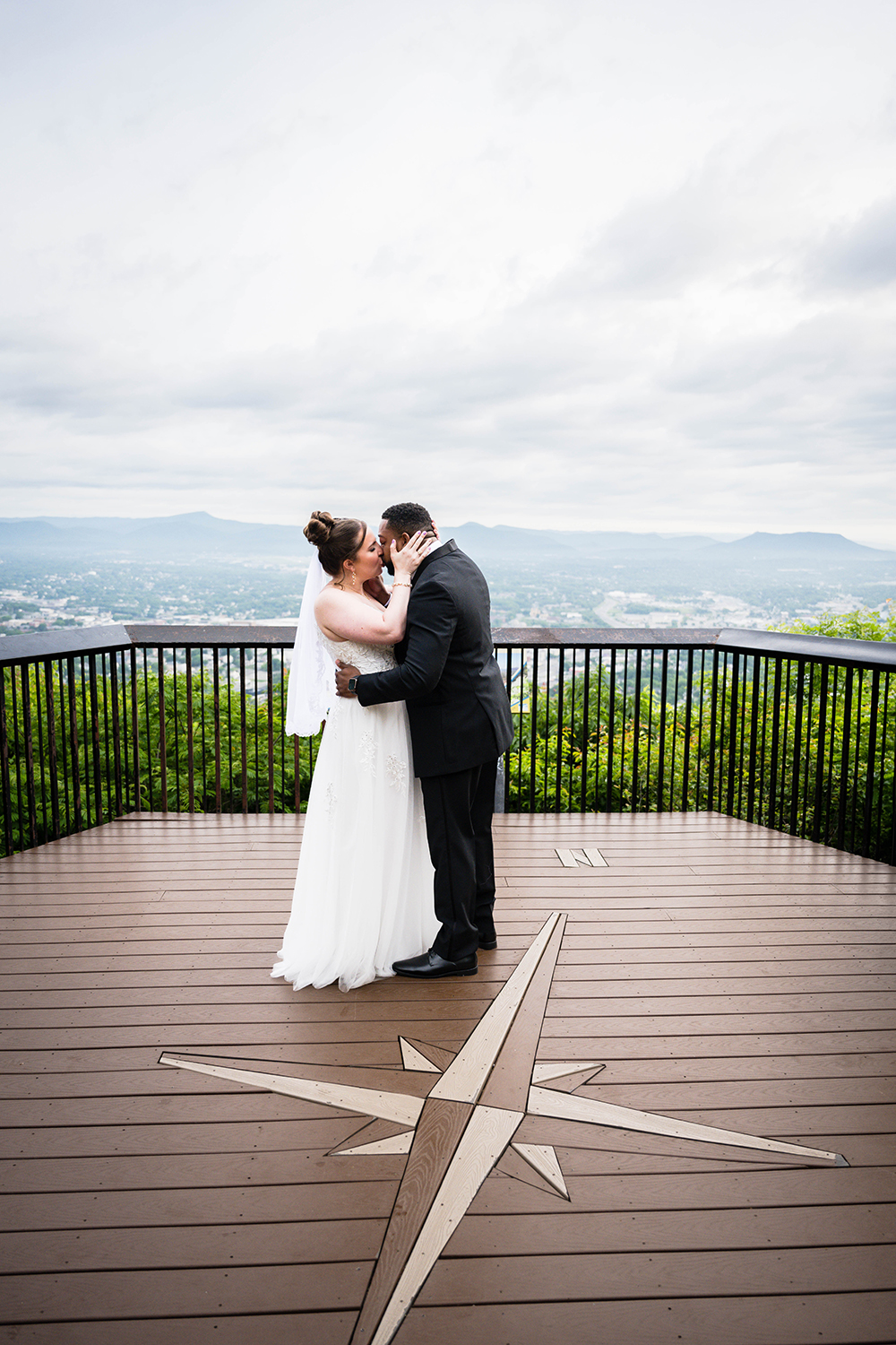 A couple on their elopement day embraces and has their first kiss at Mill Mountain Overlook. 