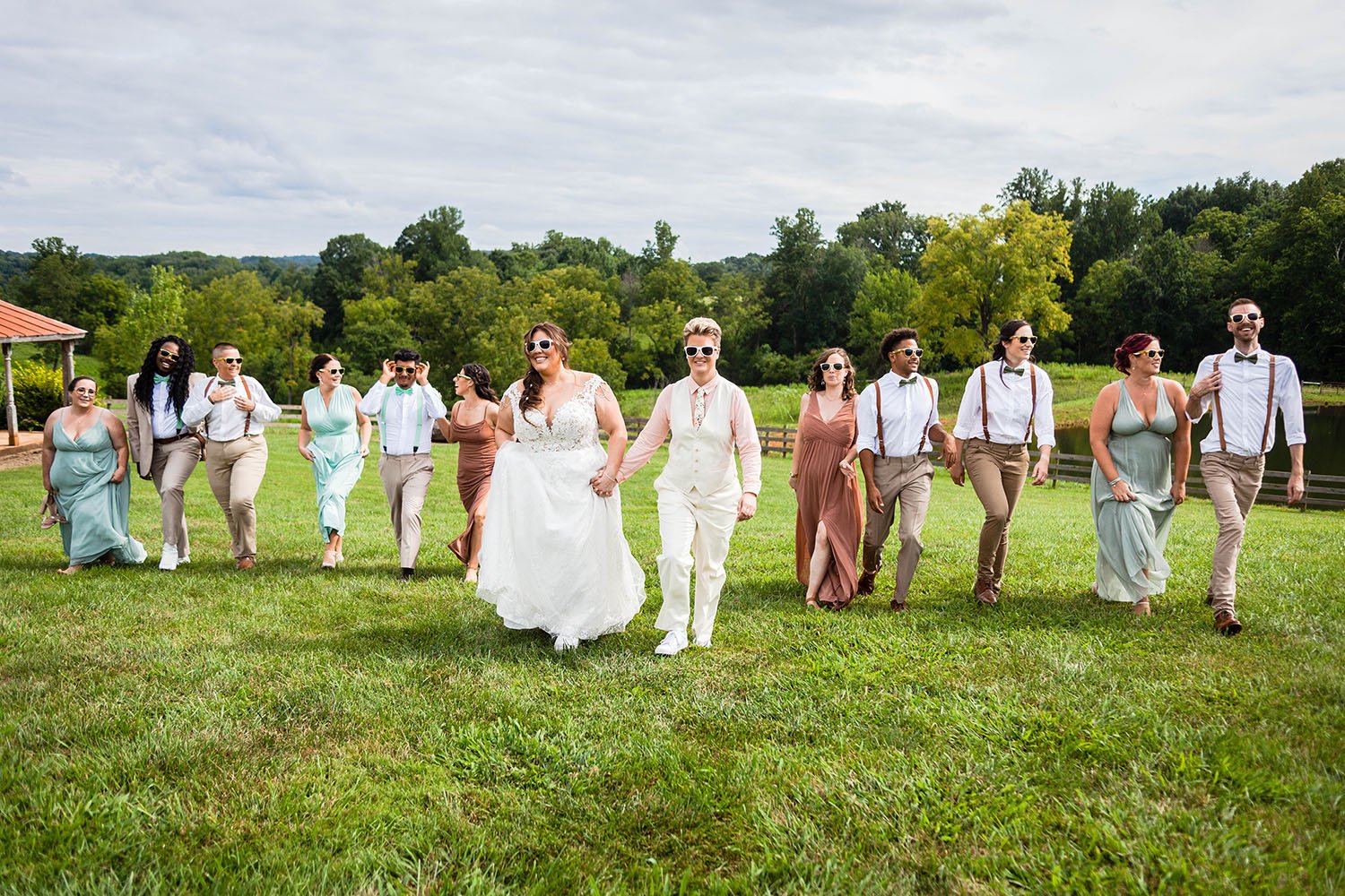 An uneven wedding party of an LGBTQ wedding couple poses in a field in Virginia.