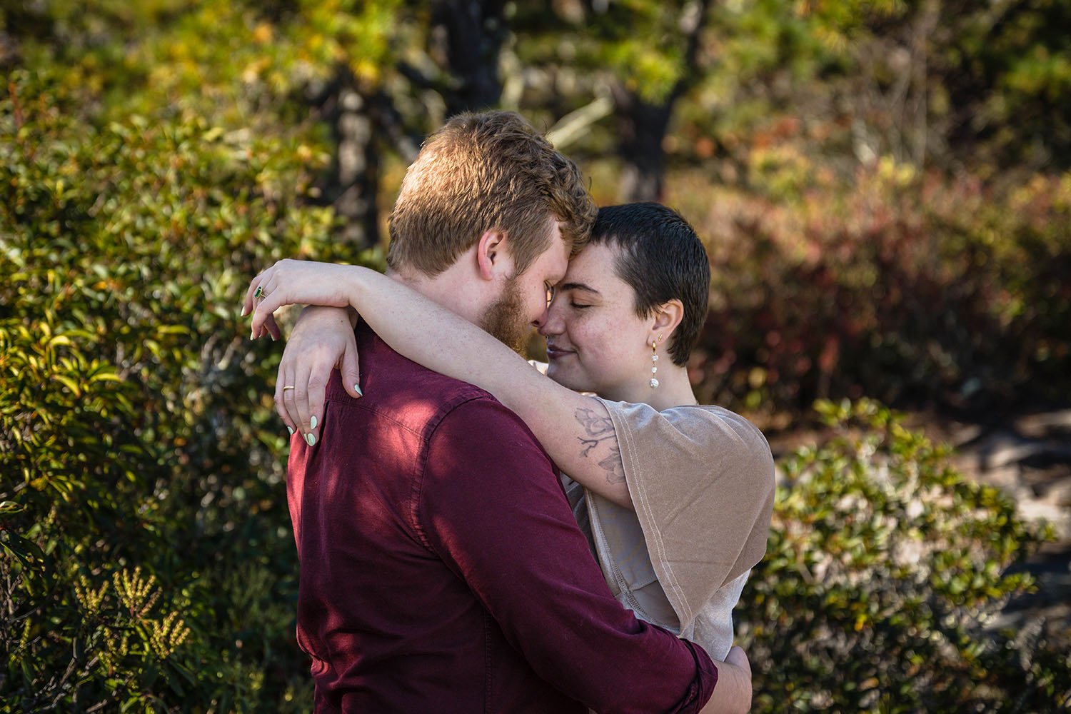 A couple embraces and touch foreheads for a photo.