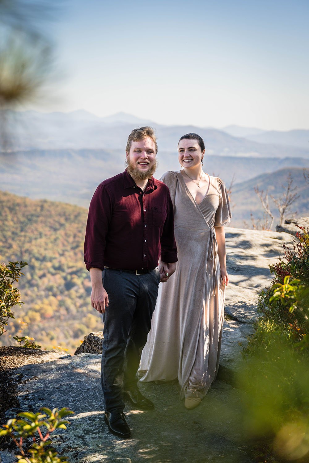 A couple holds hands and walks towards the camera for a photo during their engagement photo session at the top of McAfee Knob in Catawba, Virginia.