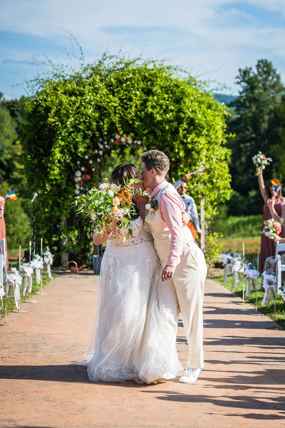 An lgbtq couple goes in for another kiss as they leave the altar and walk back down the aisle at the Pavilion at Black Water Junction.