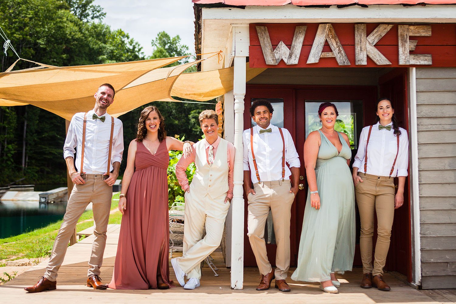 A wedding party stands outside of their wedding suite and smile for a photo.