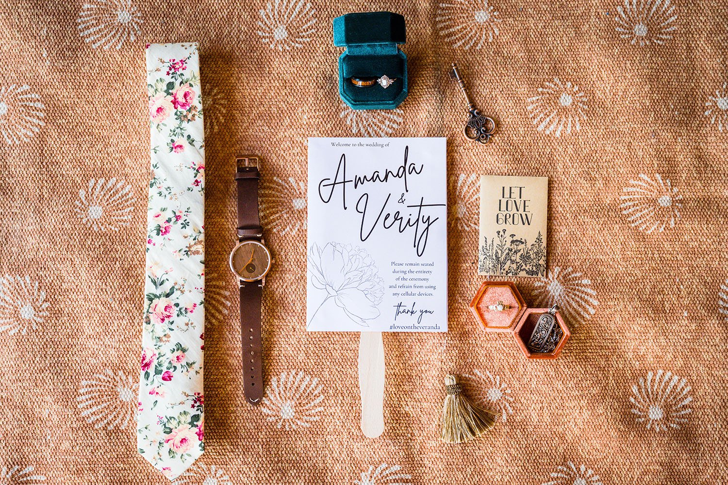 A birds eye view of a wedding details flatlay photograph featuring shoes, sunglasses, jewelry, and other accessories on a terracotta patterned carpet.