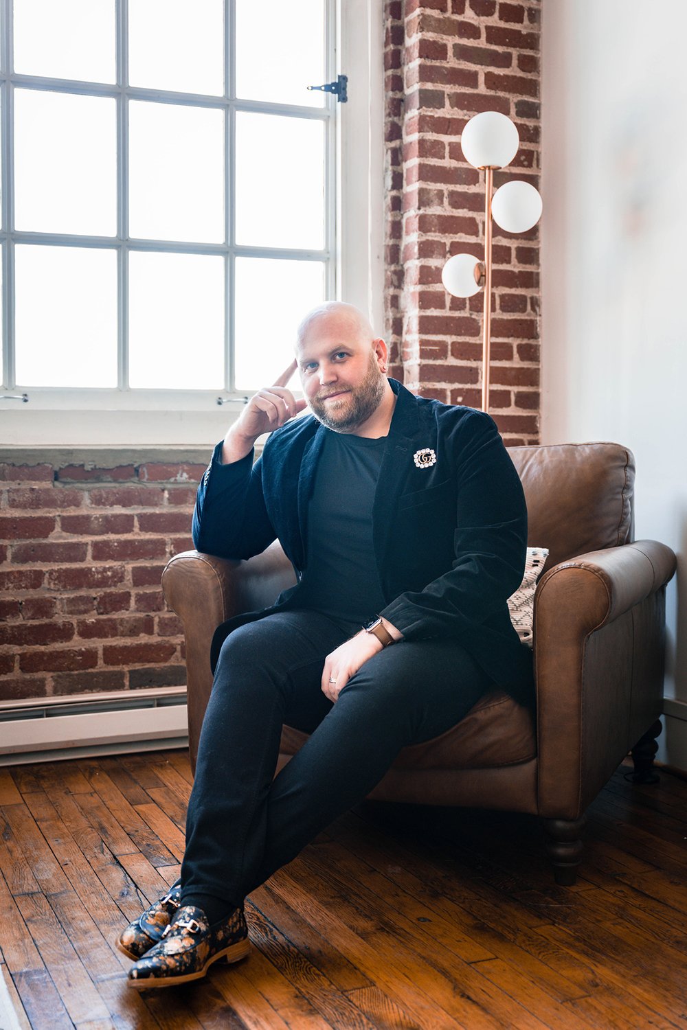 A man sits in a chair and poses during his at-home photoshoot.