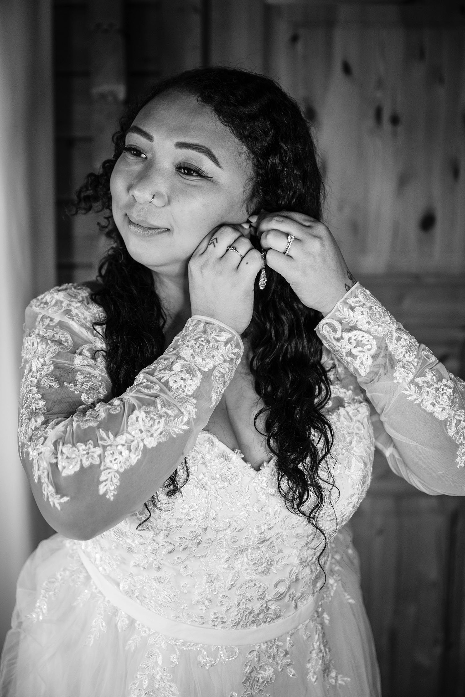 A woman adjusts her earrings inside of a wooden cabin.