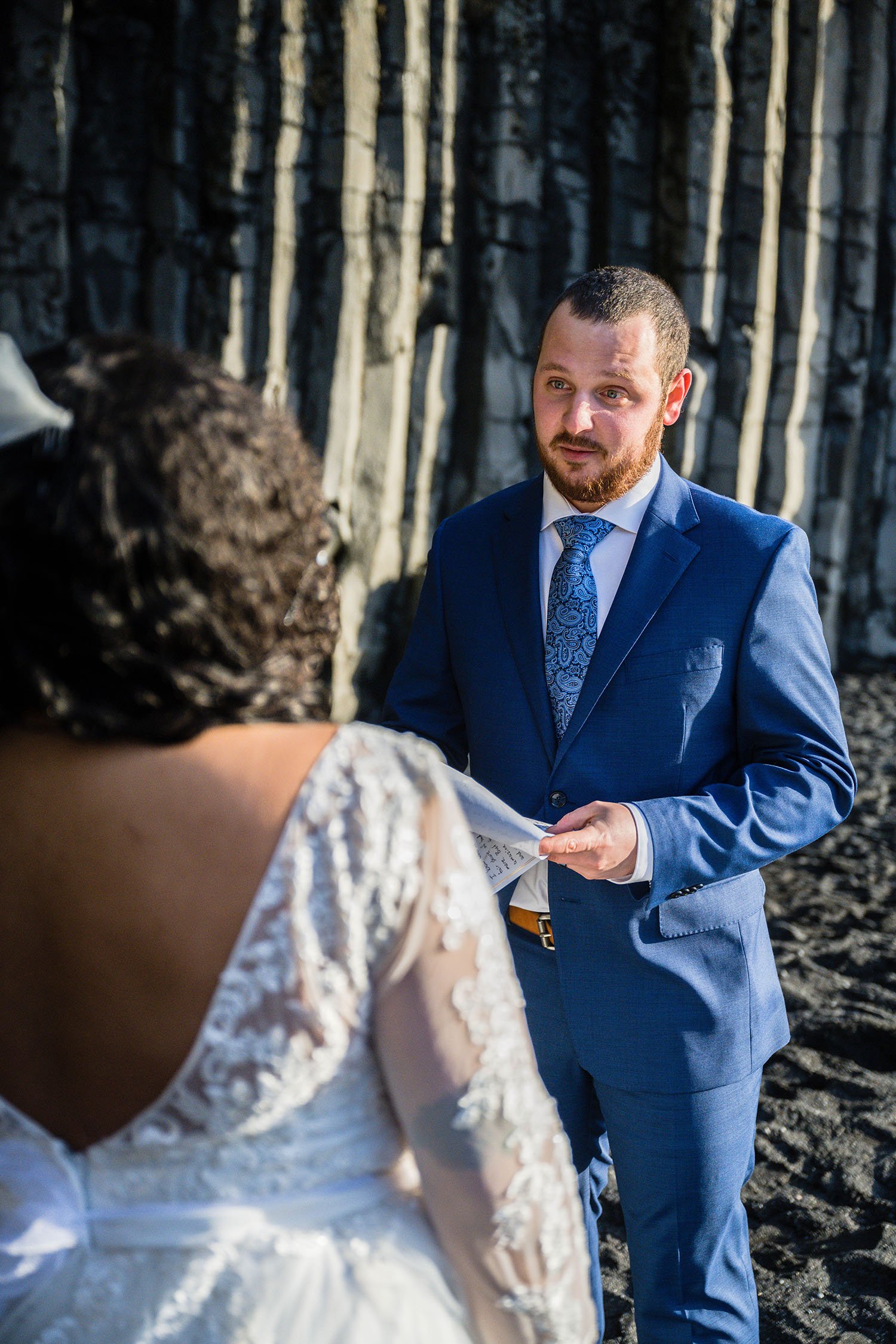 A man reads his elopement vows and looks his spouse in the eye on Reynisfjara Beach, Iceland.