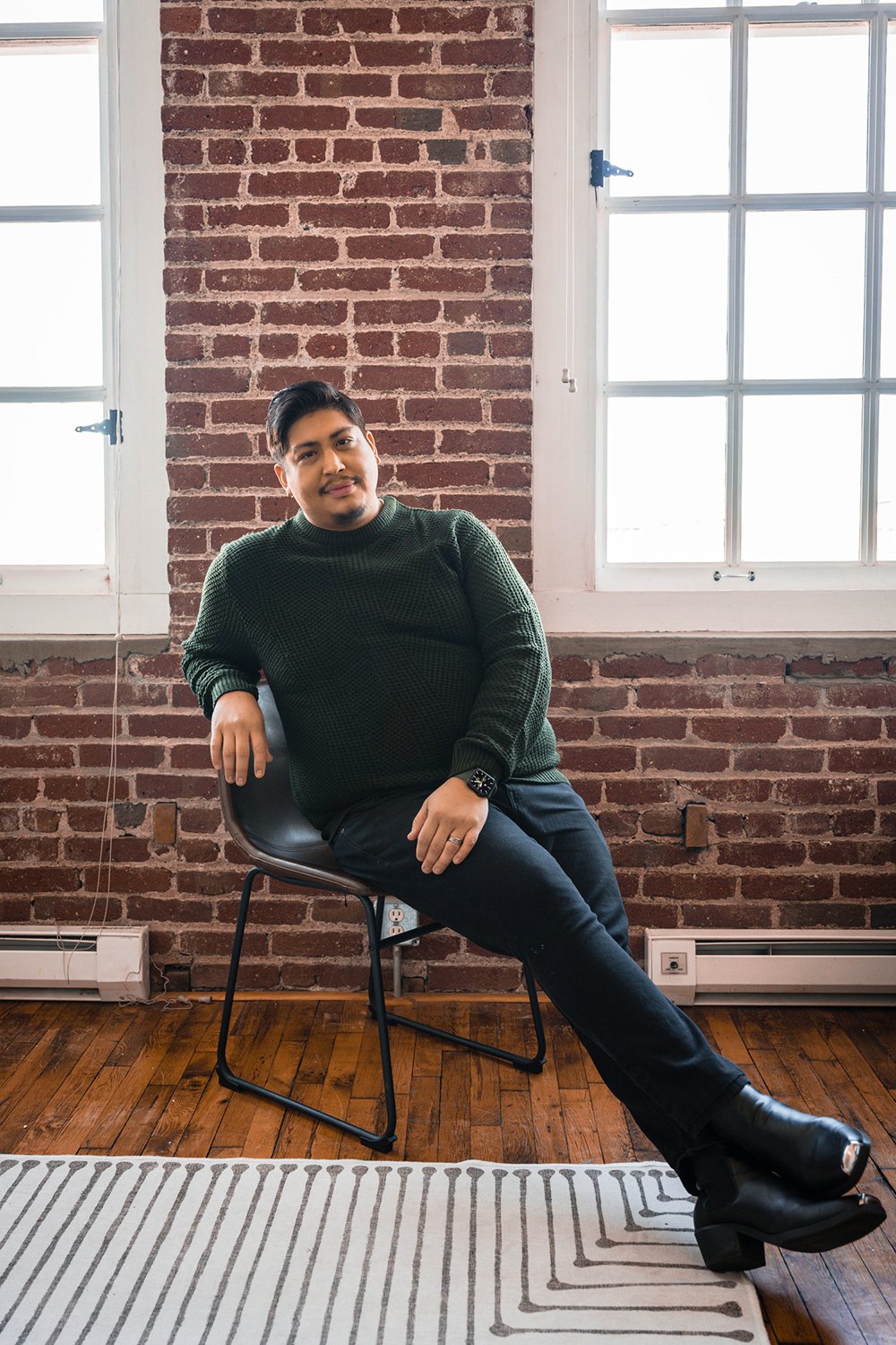 A man sits in a chair and poses during his at-home photoshoot.