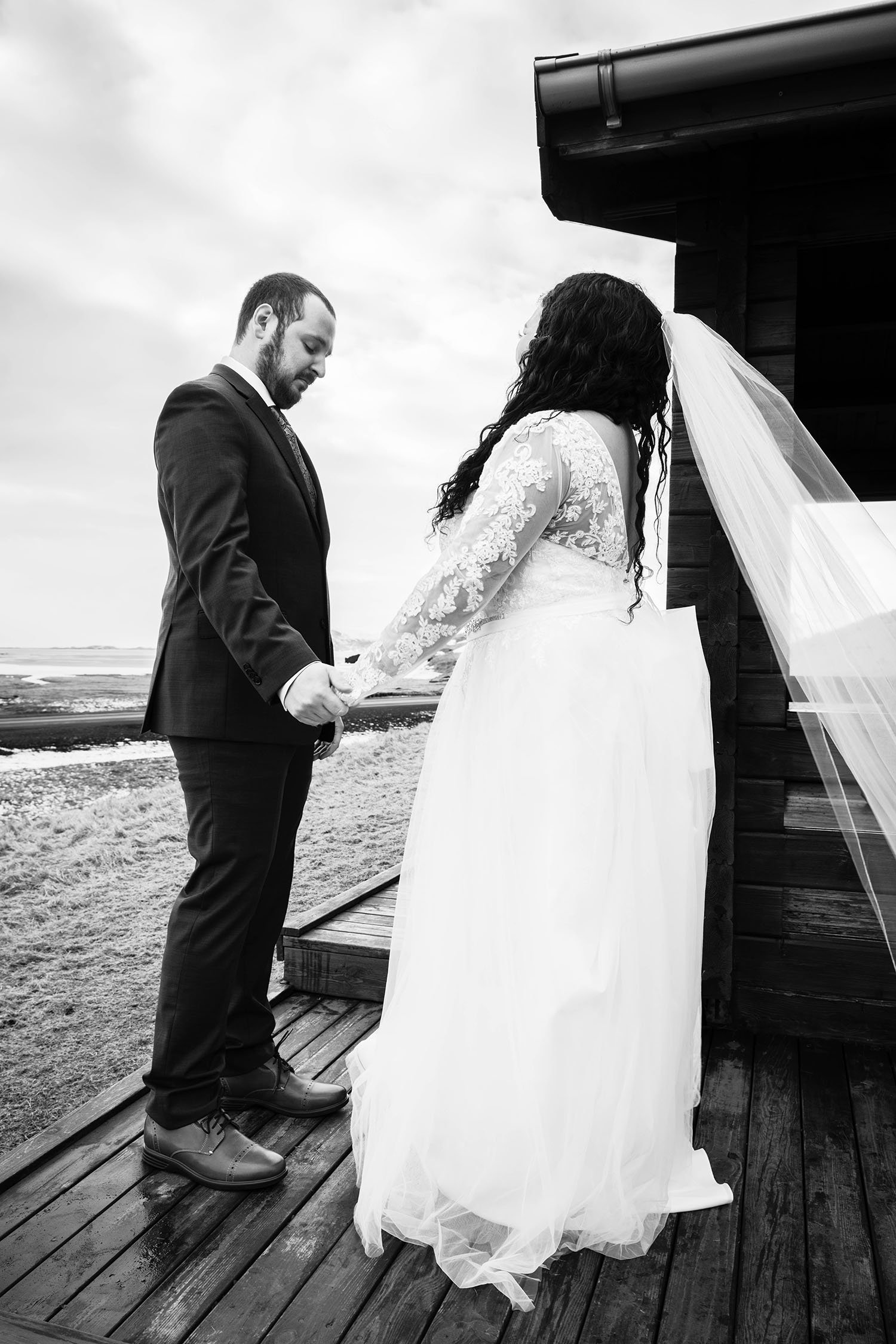 A man holds the hand of their partner and looks down teary eyed outside of their cabin in Iceland.