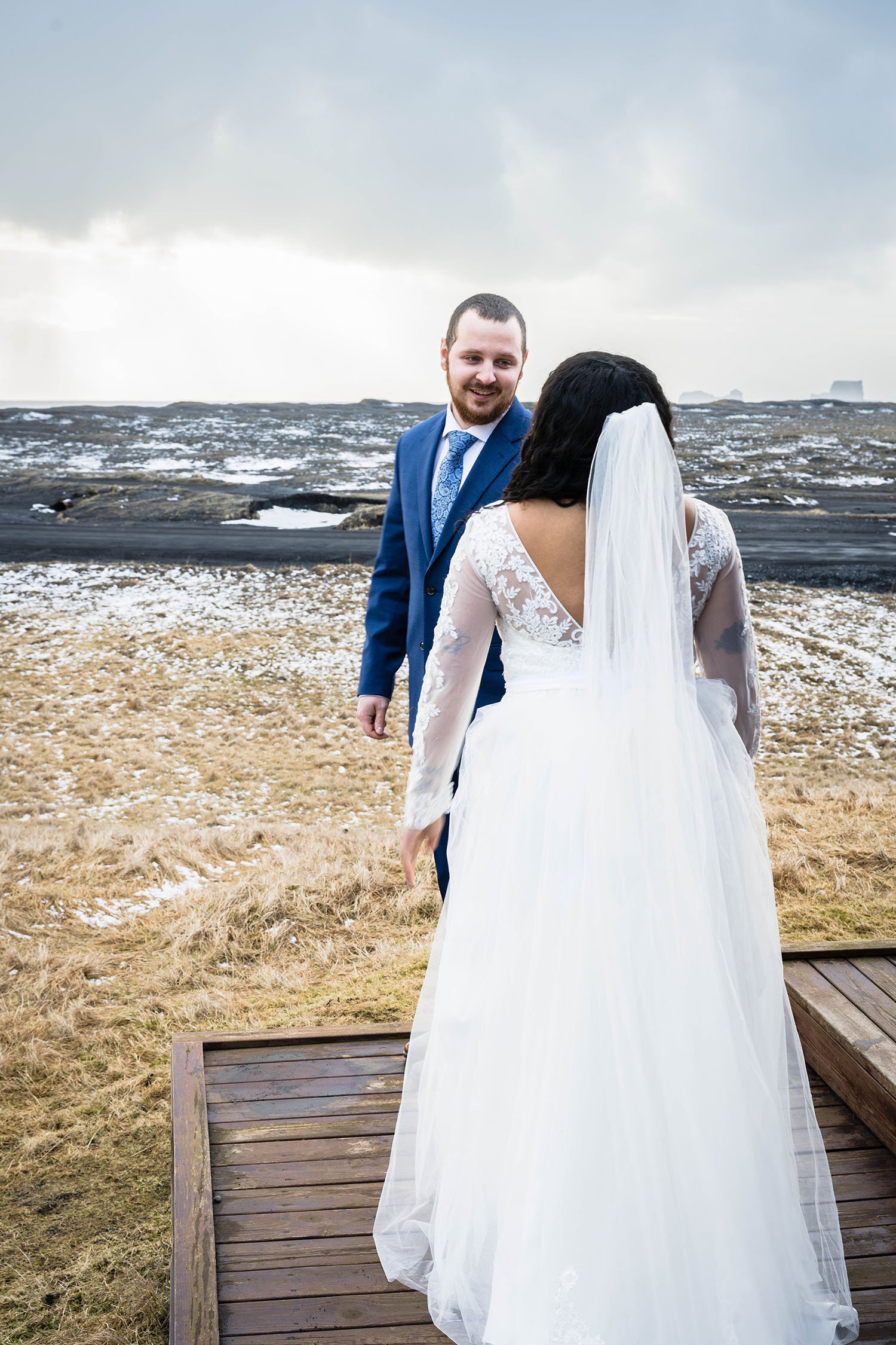 A man turns to face their partner wearing a wedding dress for their first look outside of their cabin in Iceland.