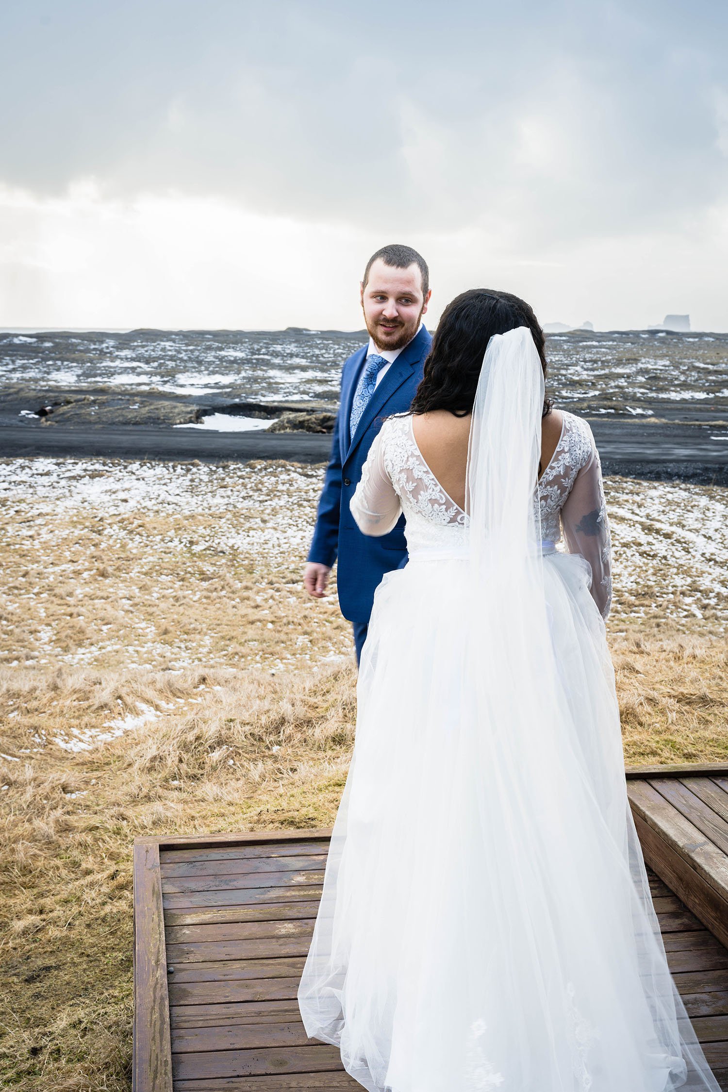 A man turns to face their partner wearing a wedding dress for their first look outside of their cabin in Iceland.