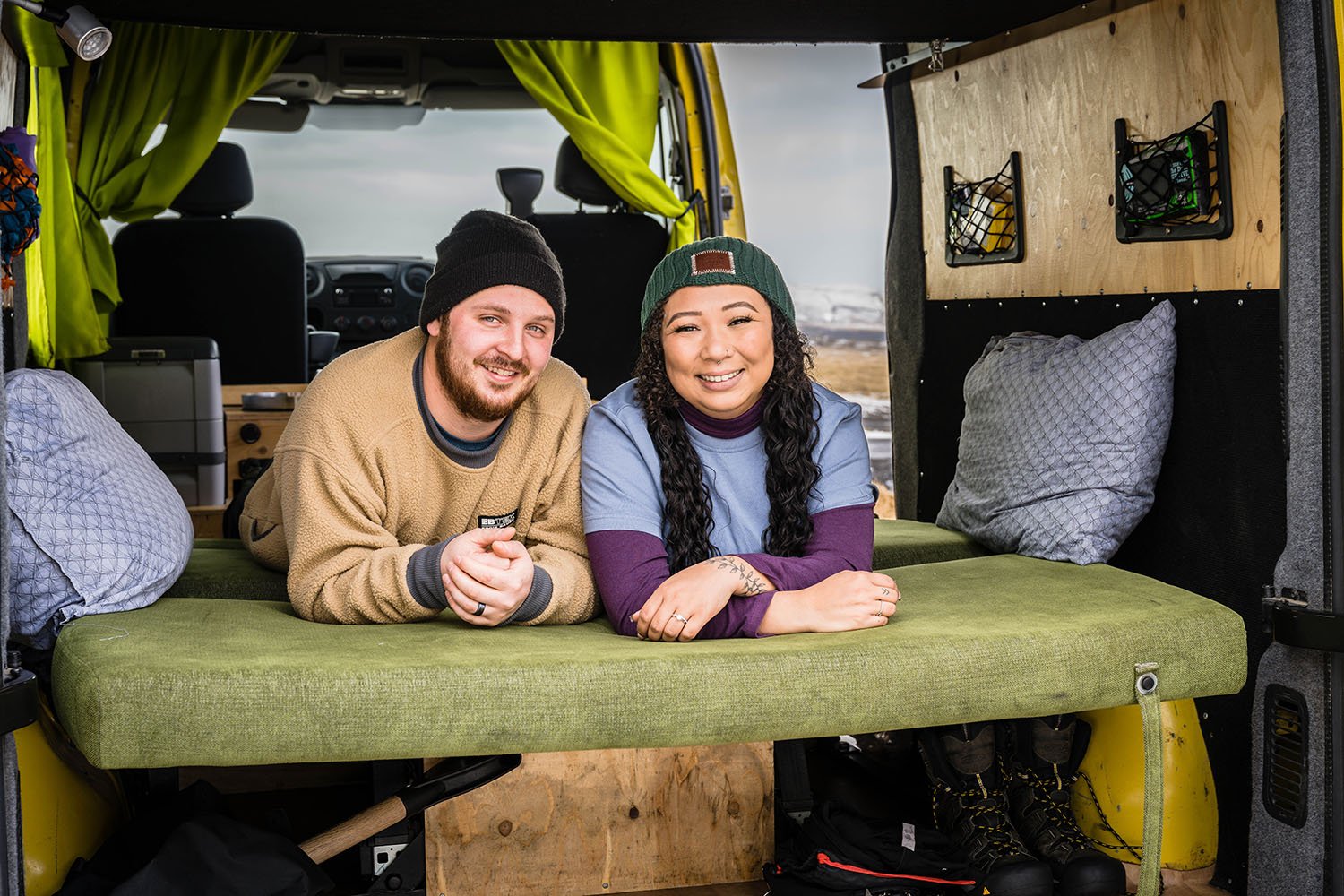 A couple lays on their stomachs on the bed in their camper van for their Iceland elopement.