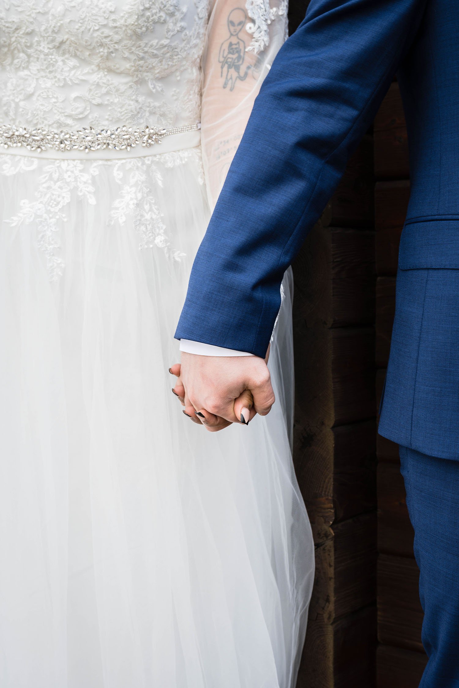 A wedding couple holds hands outside of their cabin.