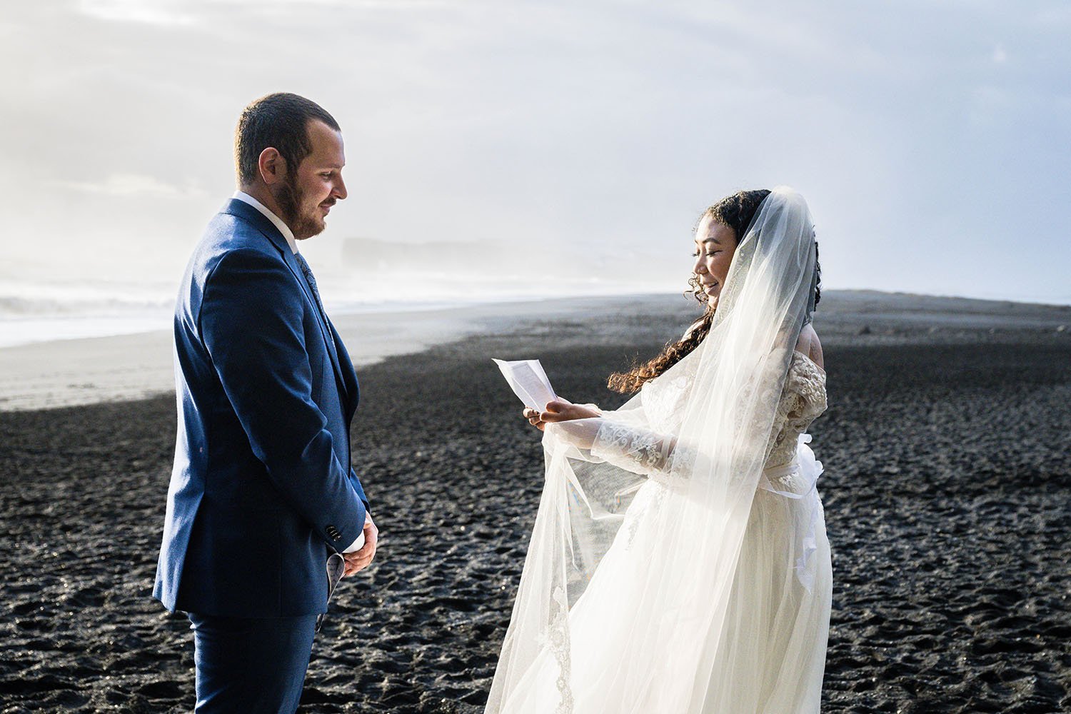 A woman reads their elopement vows on Reynisfjara Beach, Iceland.