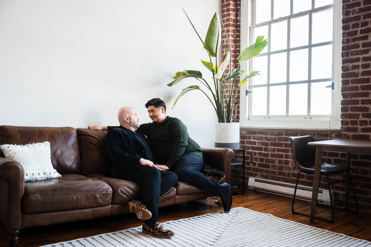 A gay couple cuddles on the couch together during their at-home photoshoot in Downtown Roanoke.