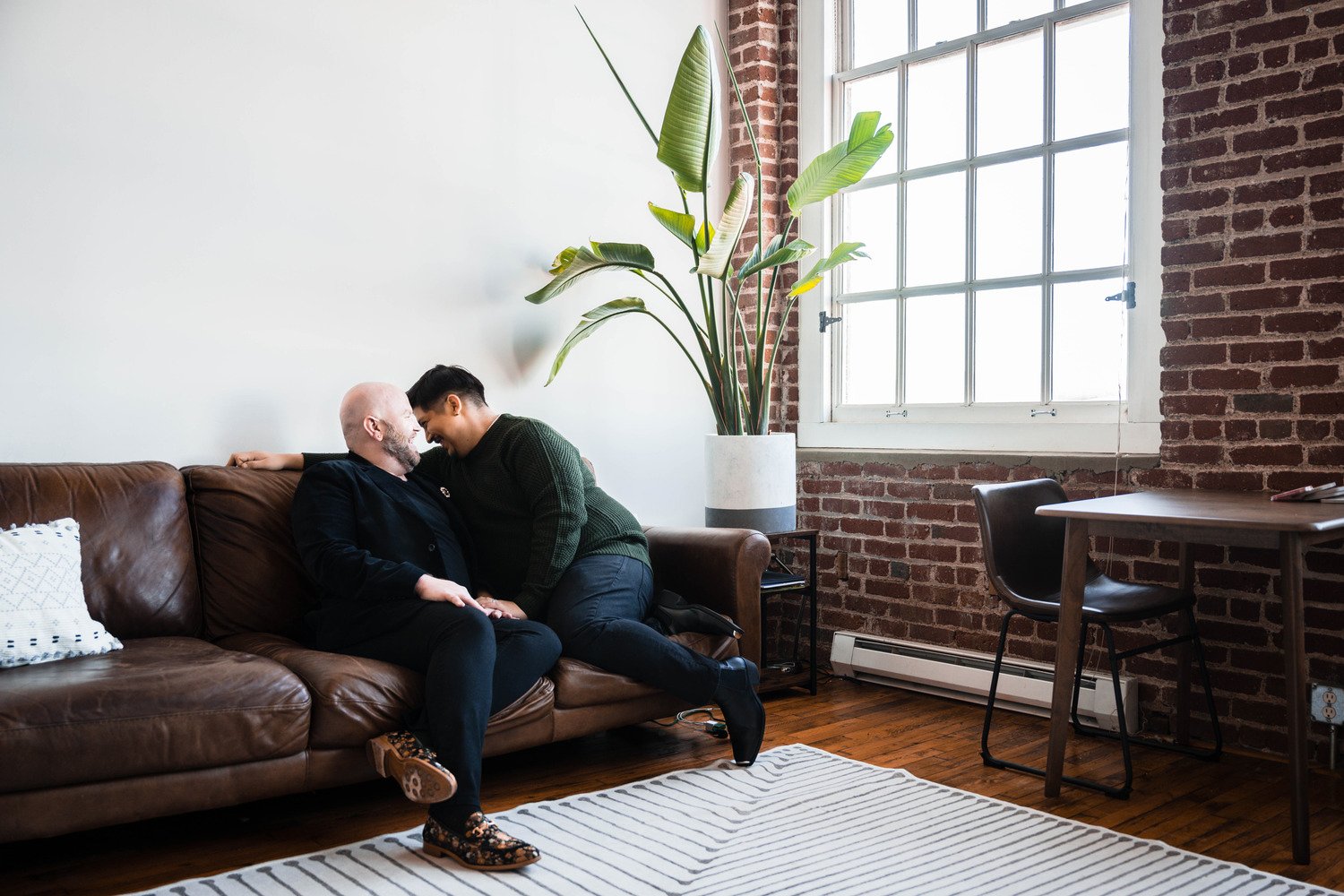 A gay couple cuddles on the couch together during their at-home photoshoot in Downtown Roanoke.