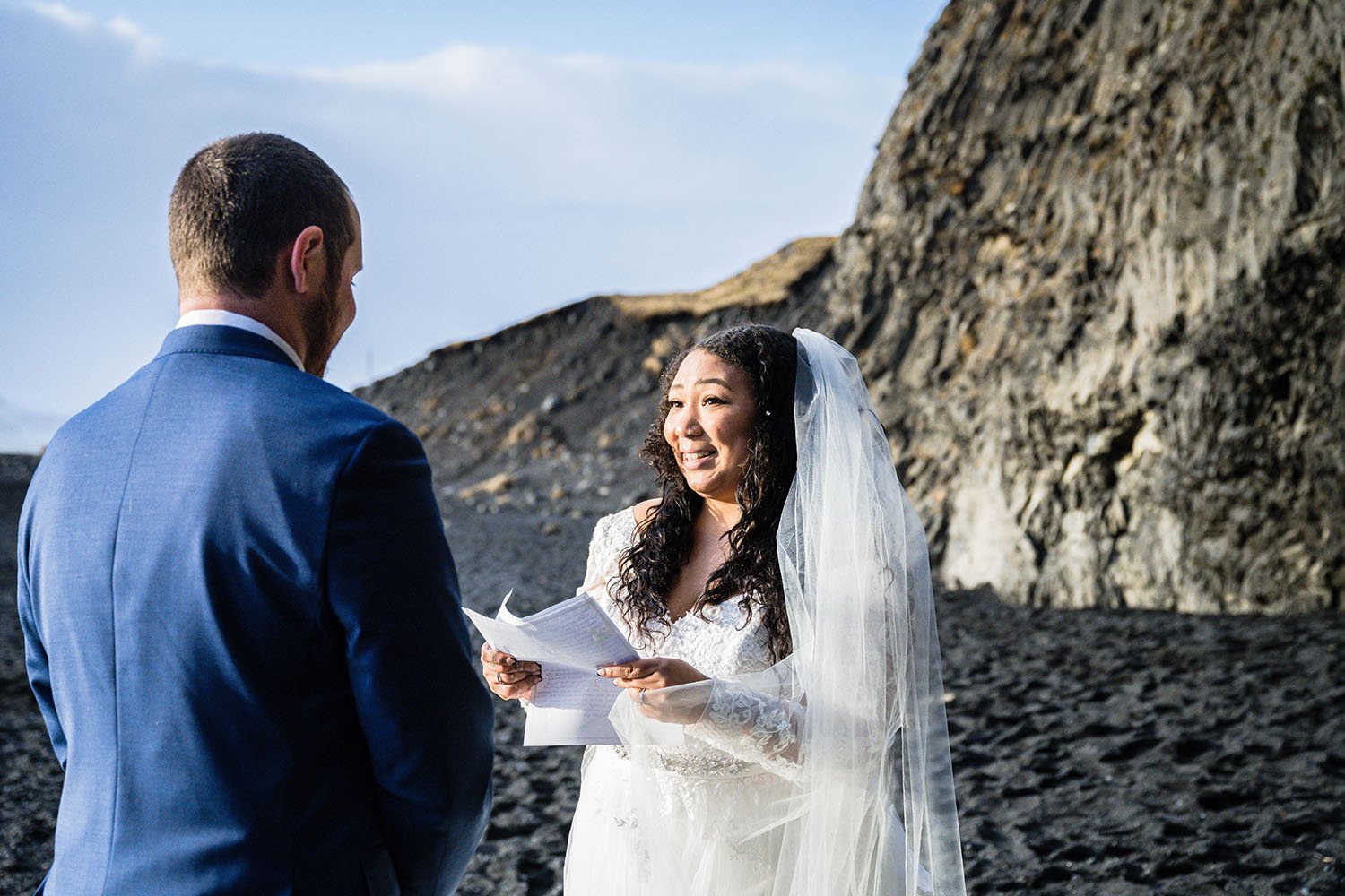 A woman reads their elopement vows and looks her partner in the eyes on Reynisfjara Beach, Iceland.