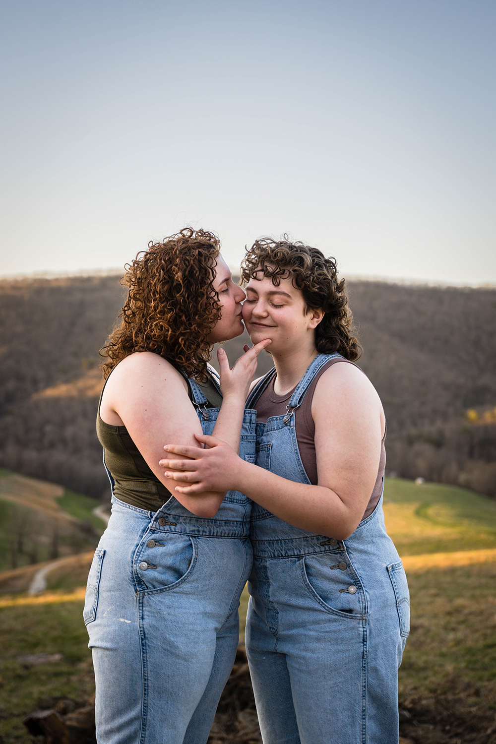 A lesbian woman kisses the cheek of their significant other during their anniversary portrait adventure session in Hidden Hills, Virginia.