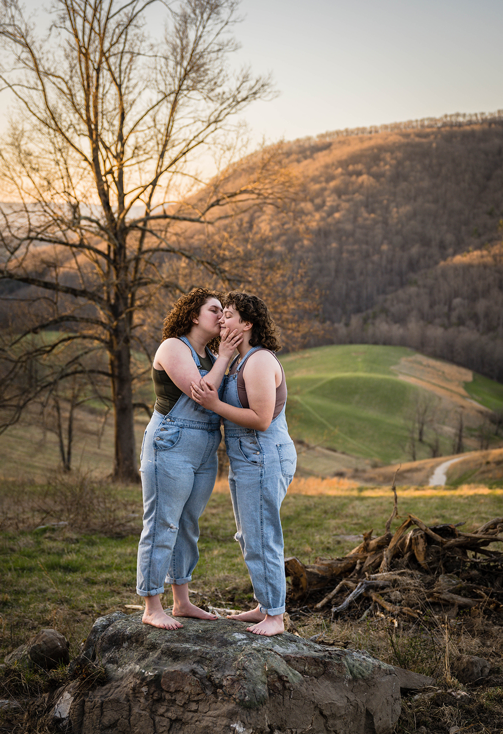 A lesbian woman kisses the cheek of their significant other during their anniversary portrait adventure session in Newport, Virginia.