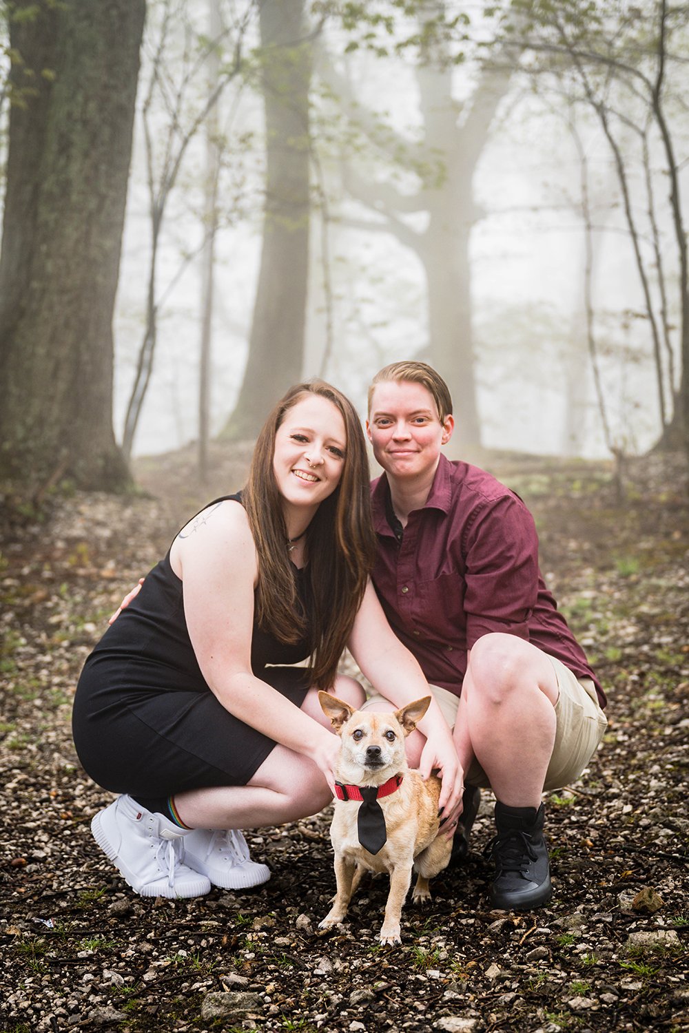 An lgbtq couple smile for the camera and hold onto their dog during their Roanoke Star engagement session.