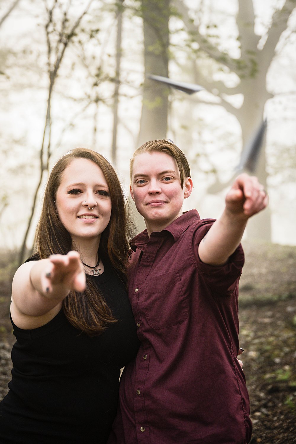 An engaged lgbtq couple throw paper airplanes towards the camera during their engagement session.