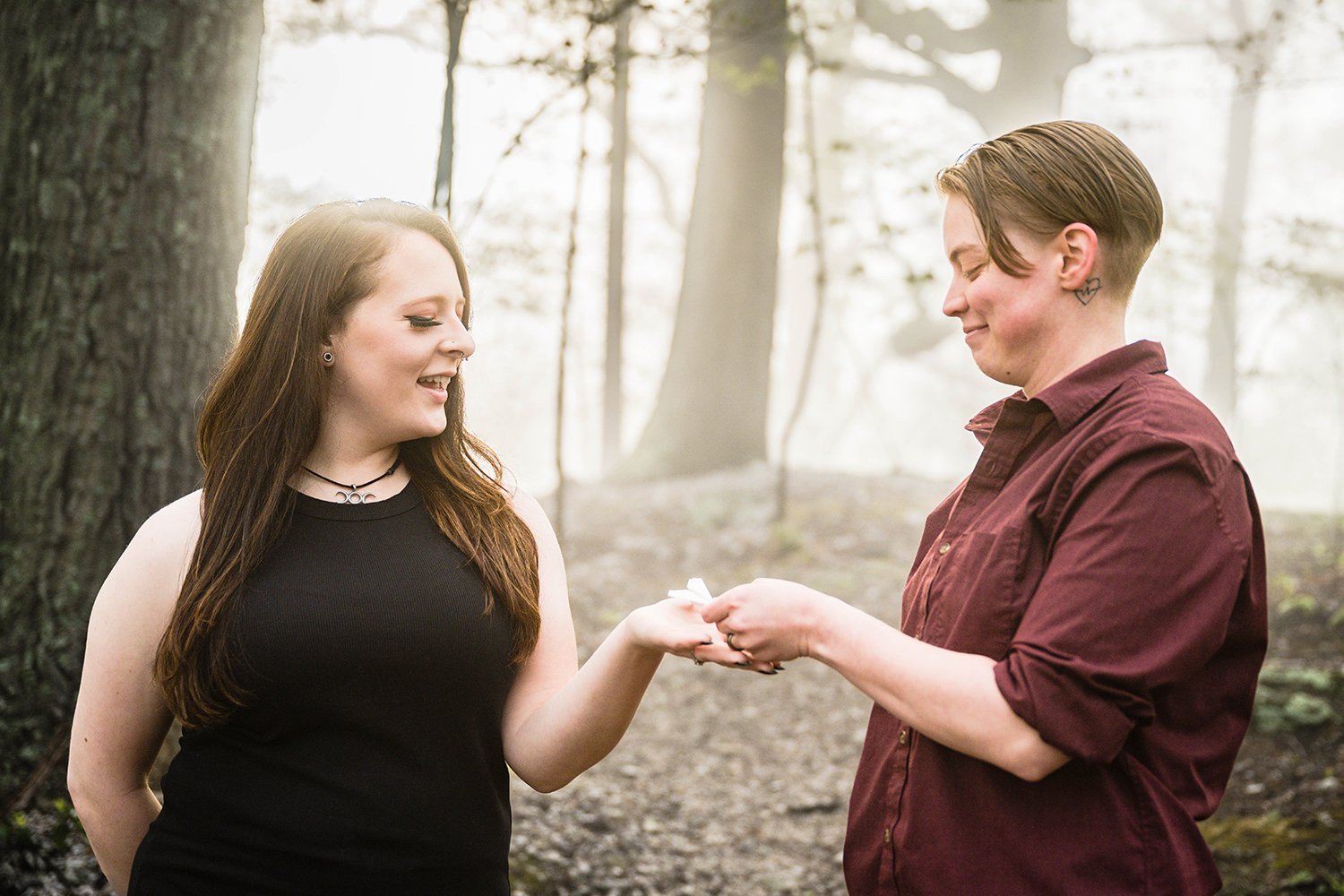 A partner places a paper airplane in the hand of their significant other during their engagement session.