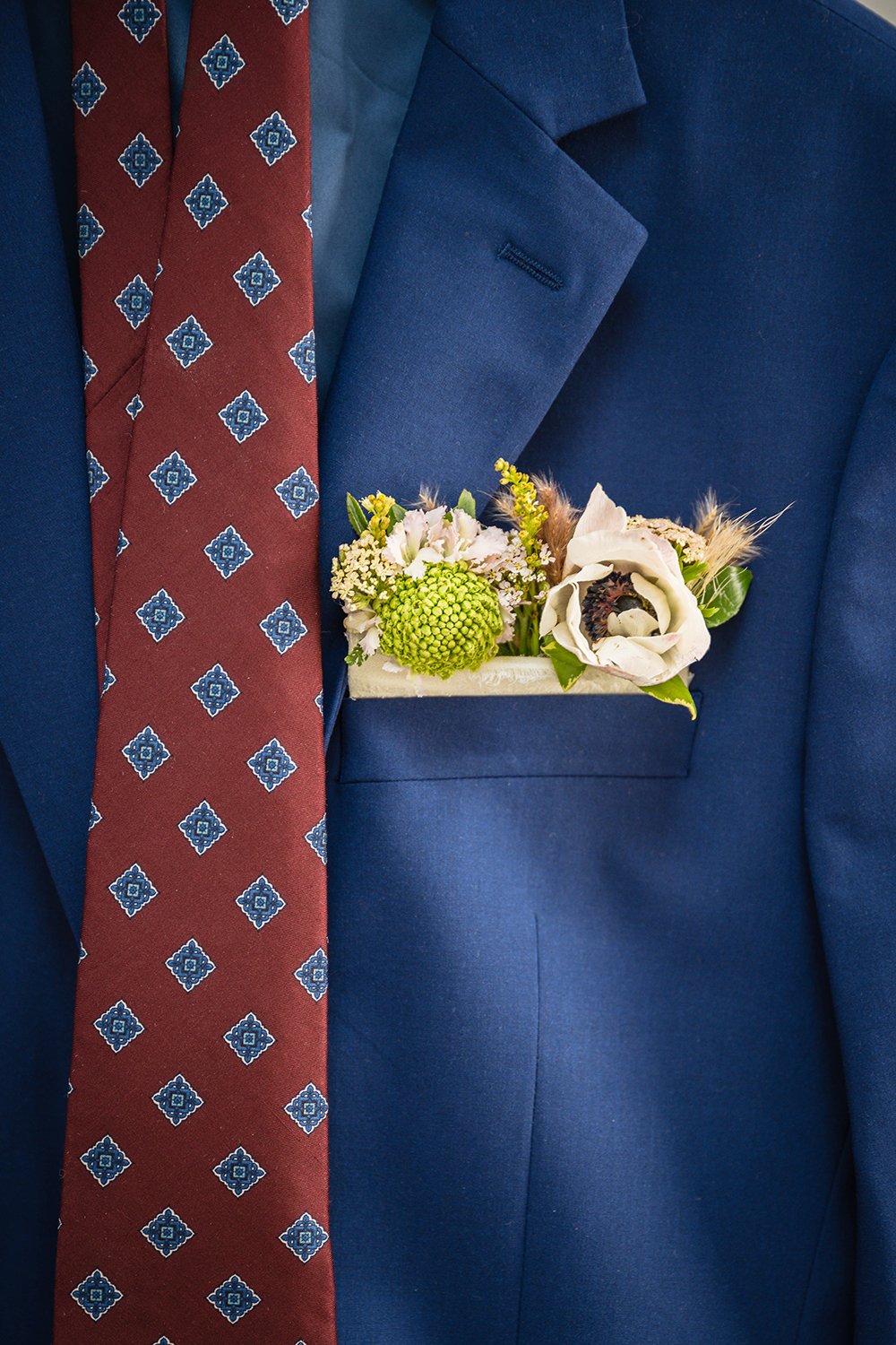 A close up detail shot of a groom's suit, tie, and floral pocket square inside Fire Station One in Downtown Roanoke.