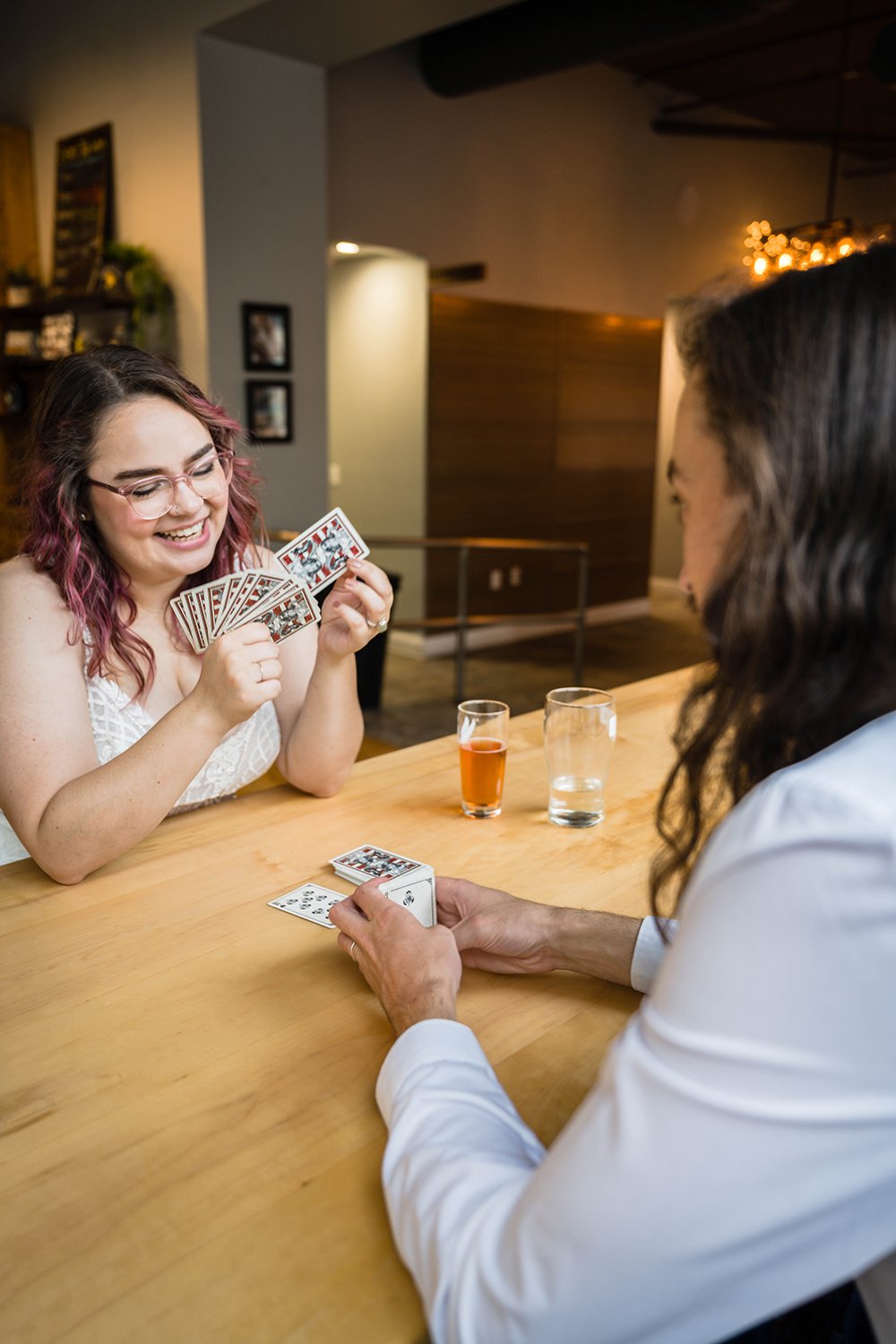 A bride looks at her hand of cards and smiles as she goes to play a card from her hand.