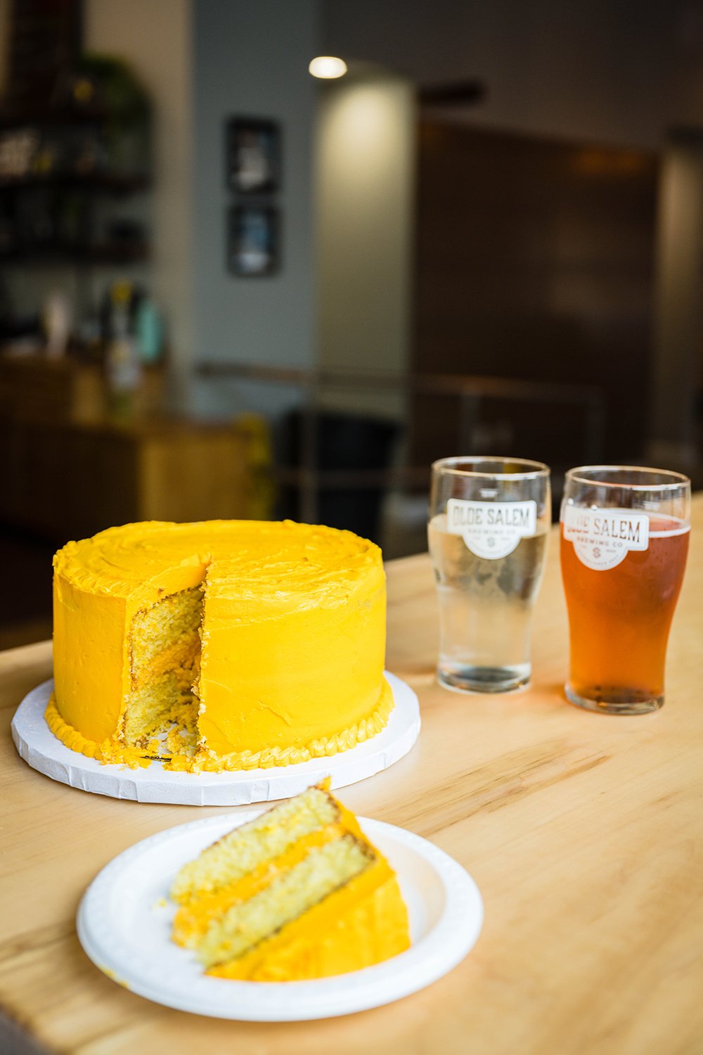 A wedding cake with a slice cut out sits beside two beers in glasses from Olde Salem Brewing Company in Downtown Roanoke.