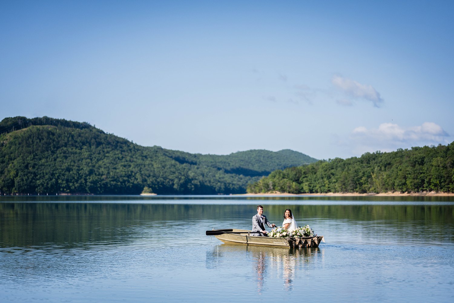 A wedding couple embark on a row boat adorned with boat florals into Carvin’s Cove in Roanoke, Virginia during their elopement.