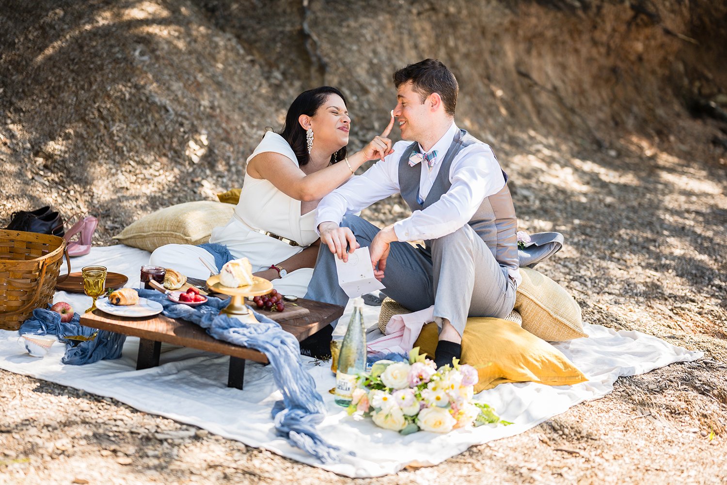 Two marriers sit along the shore of Carvin’s Cove having a brunch picnic during their elopement.